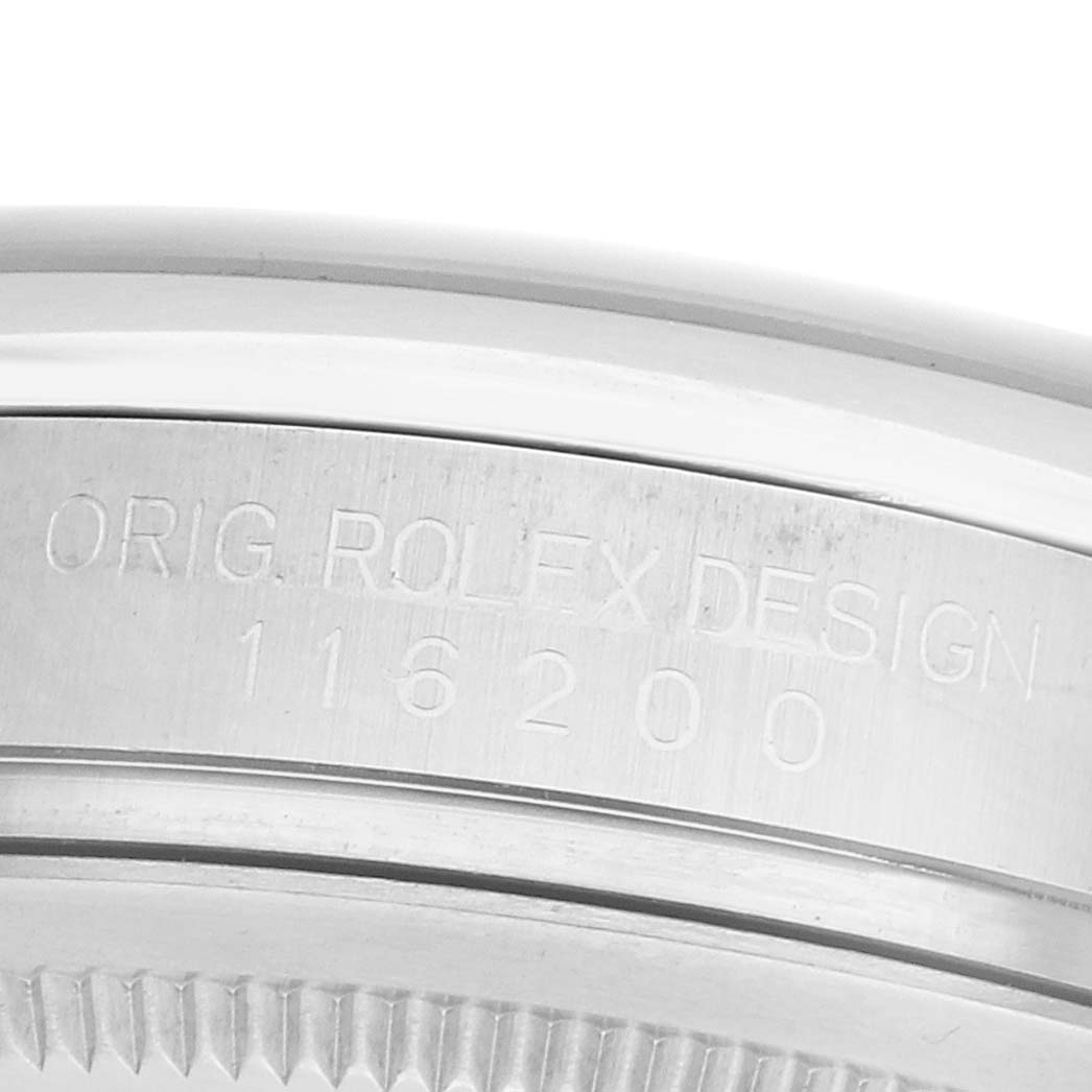 The image shows a close-up of the Rolex Datejust 116200 Men's Stainless Steel Black Dial's edge, displaying the "ORIG ROLEX DESIGN" engraving and model number 116200.