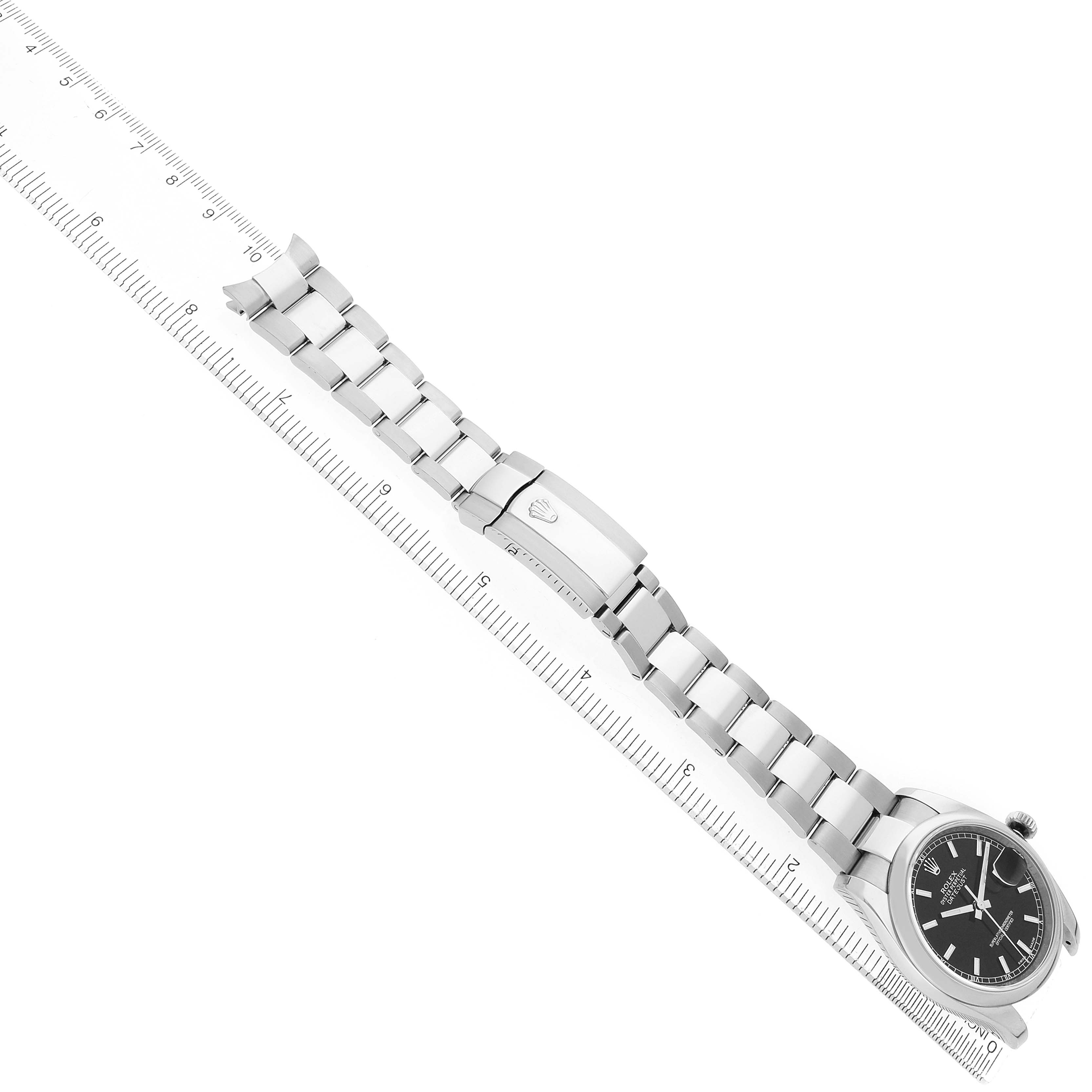 The Rolex Datejust 116200 Men's Stainless Steel Black Dial watch is shown from an angled view displaying the bracelet and clasp alongside a ruler.