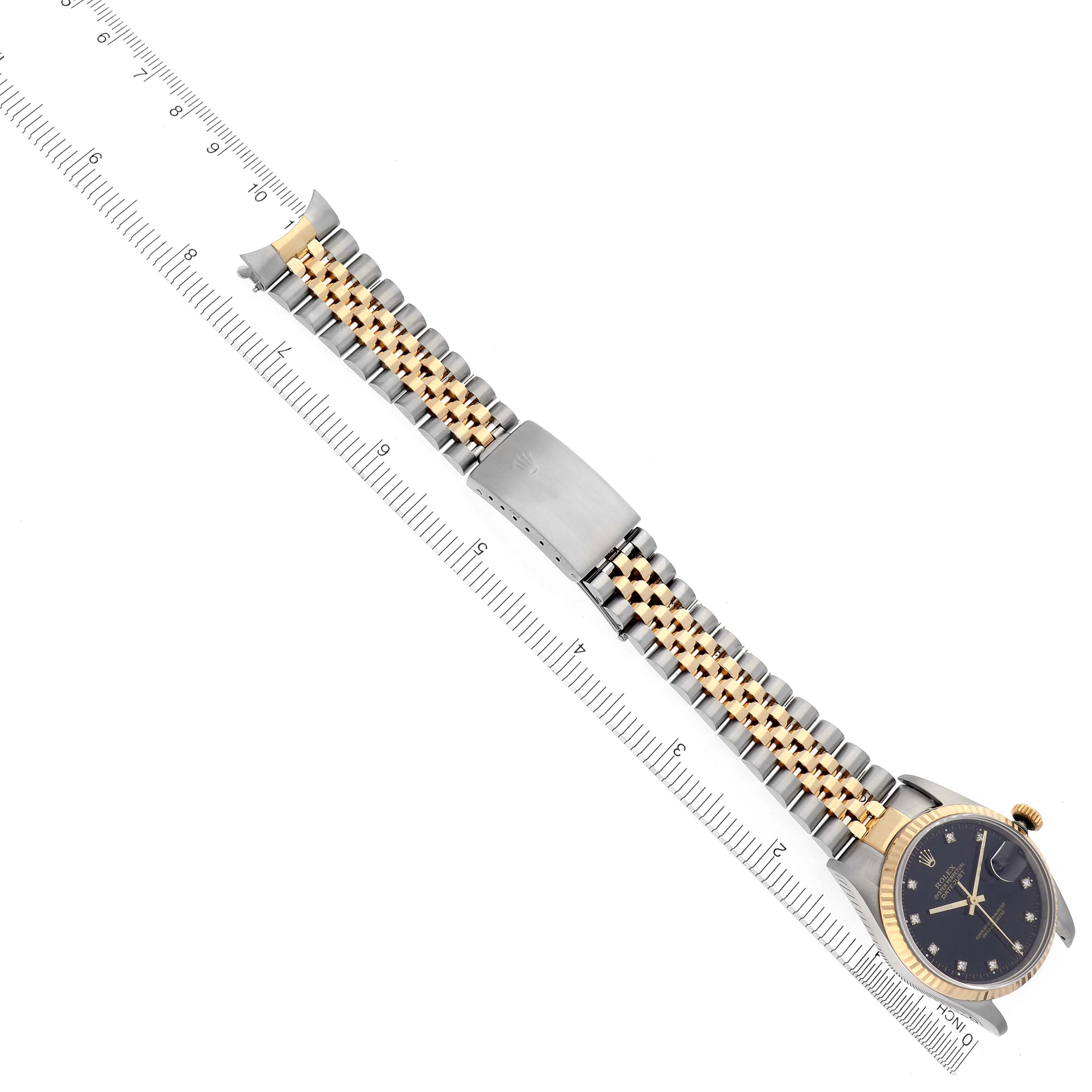 The Rolex Datejust 16233 Men's Steel and Gold (two tone) Black Dial 16233 Men's Steel and Gold (two tone) Black Dial watch is shown at an angle highlighting the face, two-tone bracelet, and clasp alongside a ruler for scale.