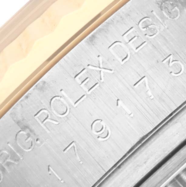 The image shows a close-up of the engraved side of a Rolex Datejust 179173 Women's Steel and Gold (two tone) White Dial 179173 Women's Steel and Gold (two tone) White Dial watch case.