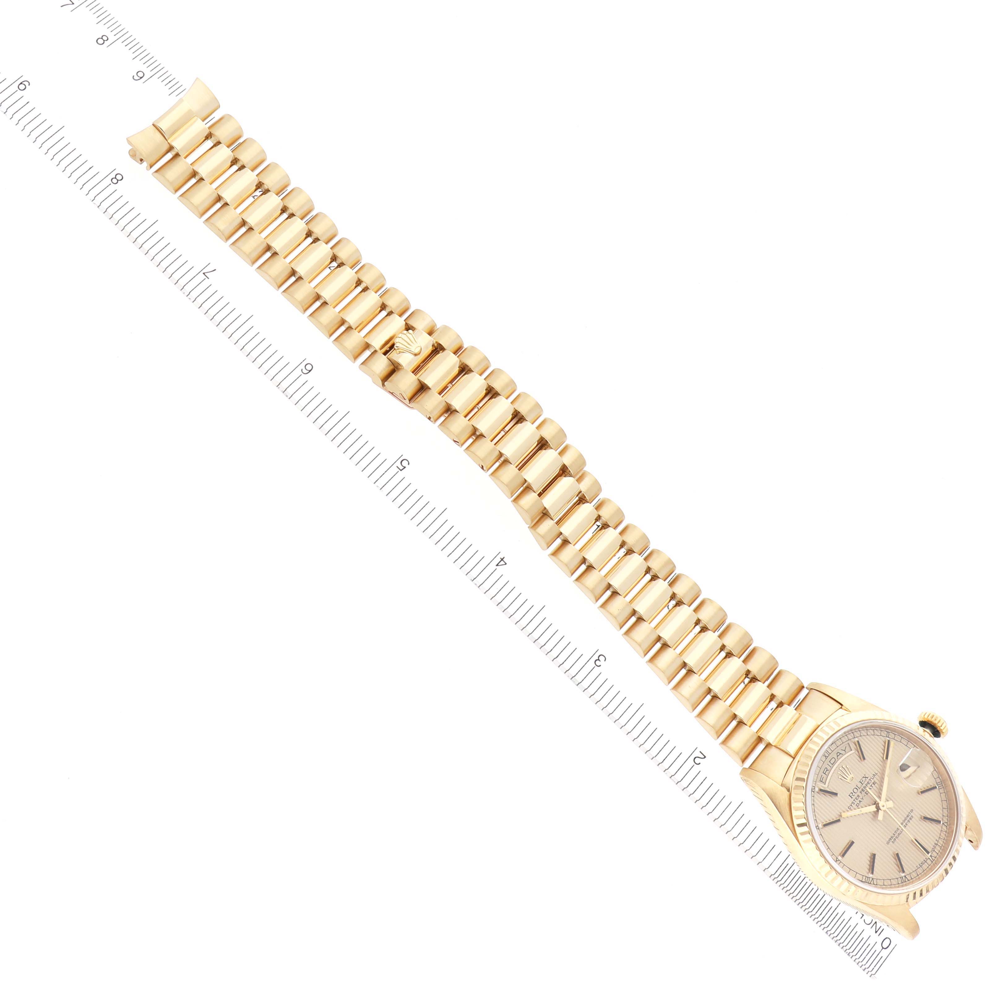 The image shows a Rolex President 18238 Men
s Yellow Gold Champagne Dial 18238 Men
s Yellow Gold Champagne Dial model watch at a top-down angle, displaying the dial, bracelet, and part of the clasp beside a ruler.