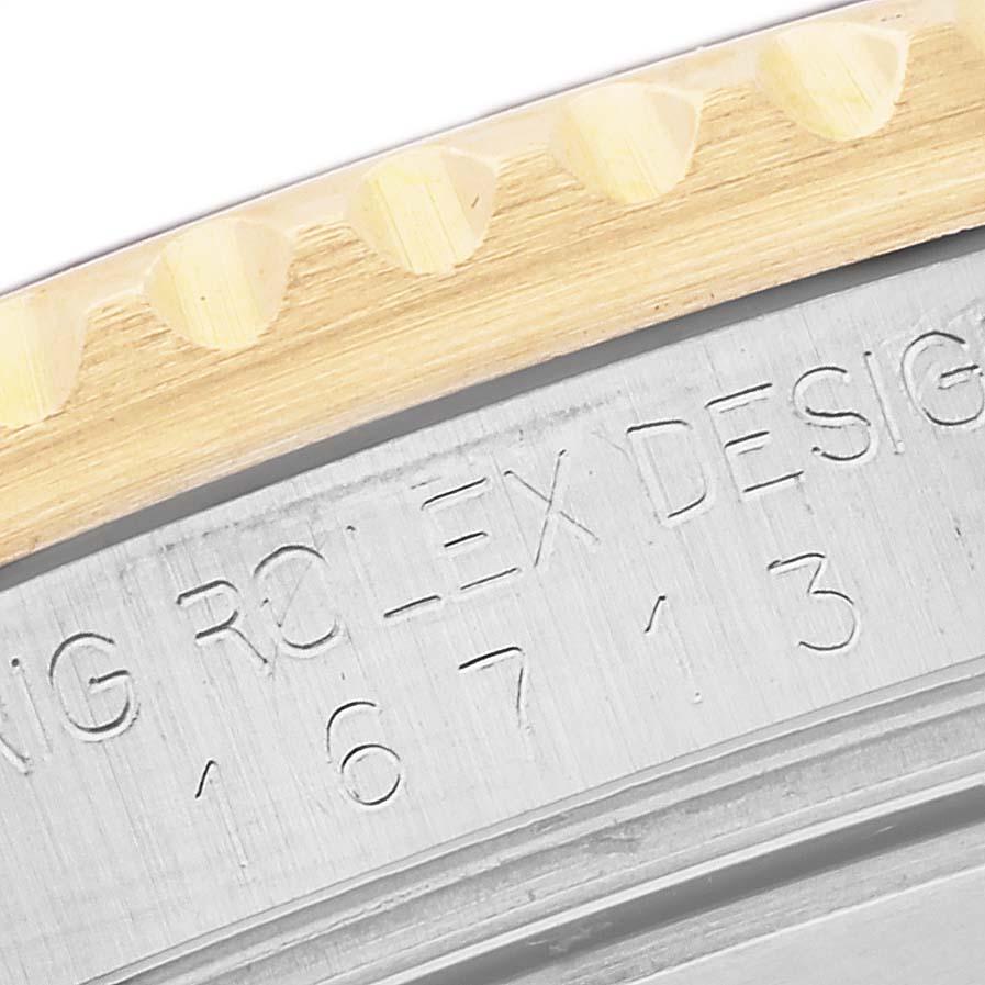 The image shows a close-up of the Rolex GMT-Master 16713 Men's Steel and Gold (two tone) Black Dial 16713 Men's Steel and Gold (two tone) Black Dial's engraved case and part of the gold bezel edge.