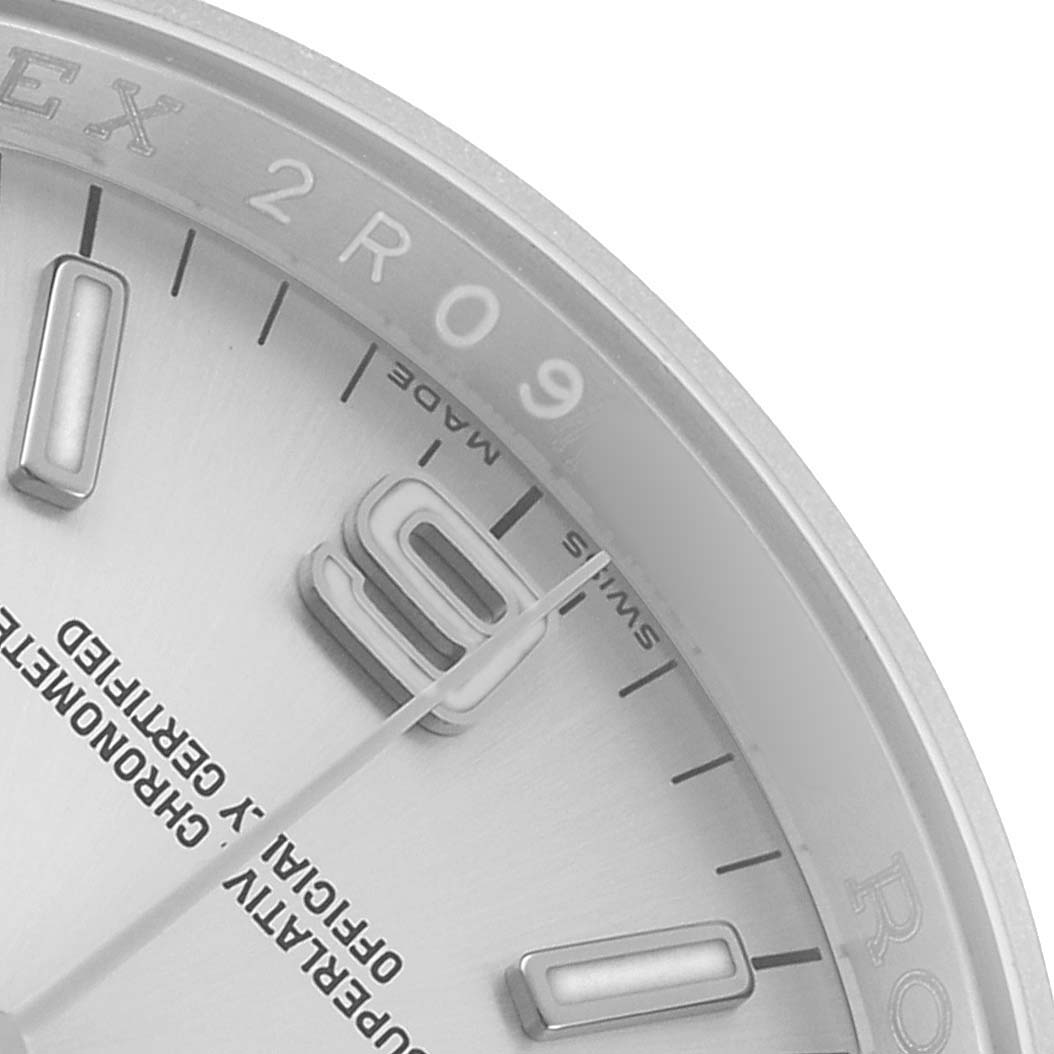 The image shows the upper right part of the Rolex Oyster Perpetual 116000 Men's Stainless Steel Silver Dial watch face, including hour markers and partial branding.