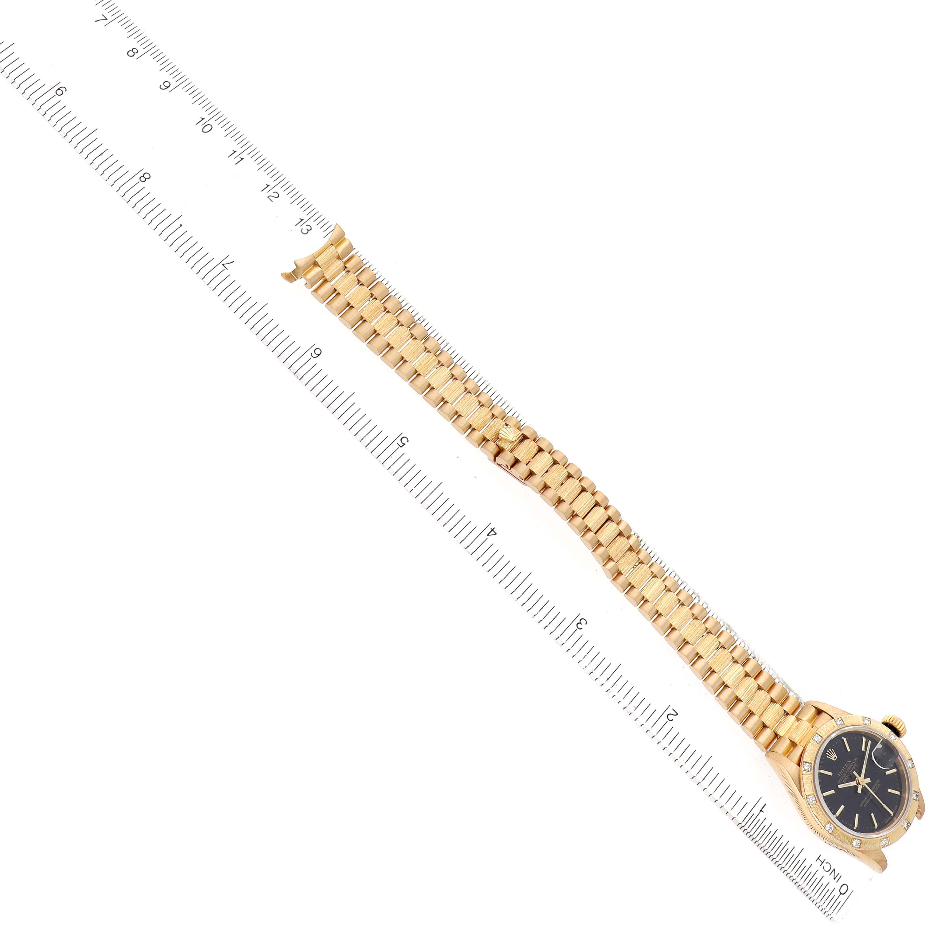 The image shows a Rolex President 69288 Women's Yellow Gold Black Dial model watch from a top-down angle, highlighting the bracelet, dial, and case beside a ruler.