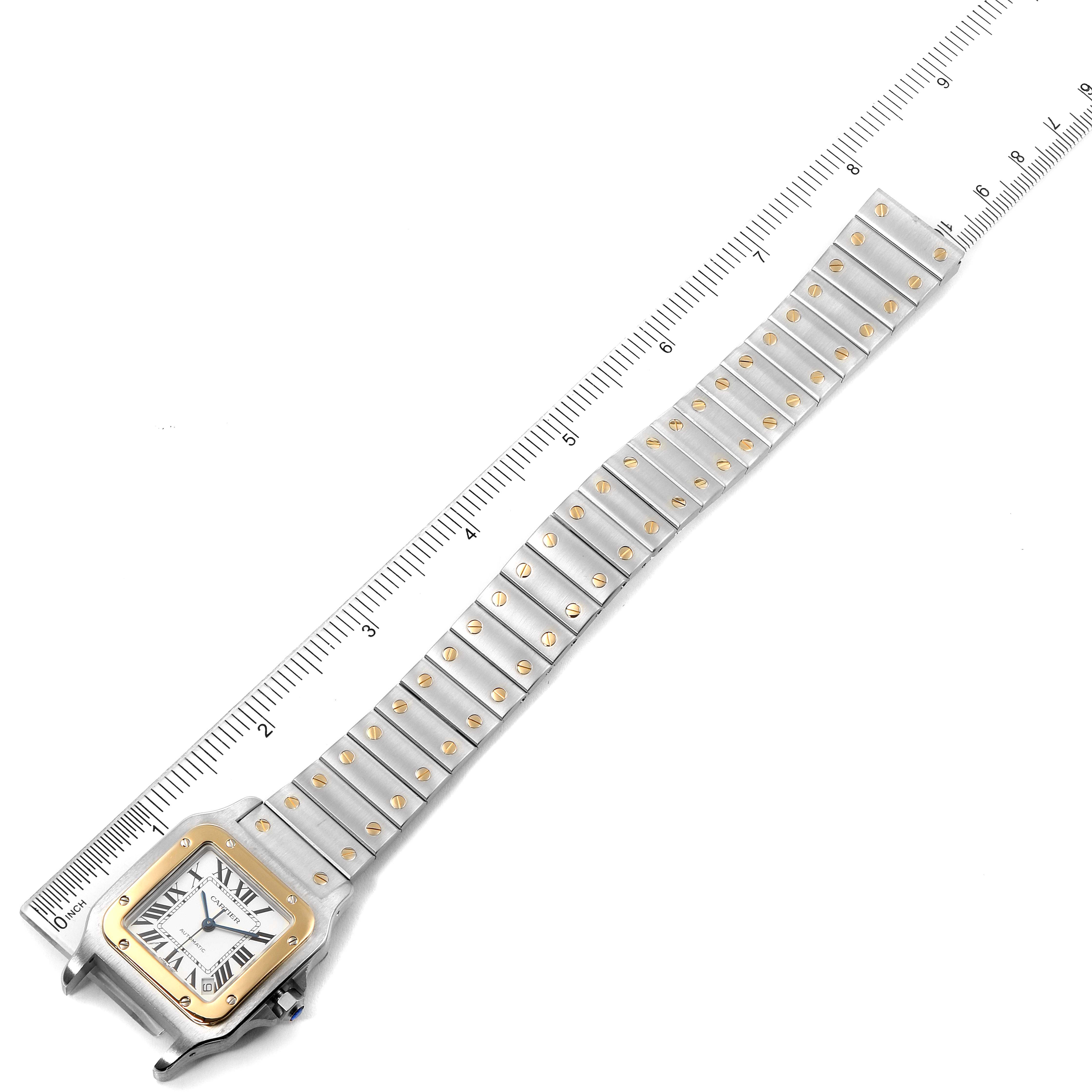 The image shows a Cartier Santos W20099C4 Men's Steel and Gold (two tone) Silver Dial W20099C4 Men's Steel and Gold (two tone) Silver Dial watch, displaying its face, bezel, and bracelet, laid flat next to a measuring scale.