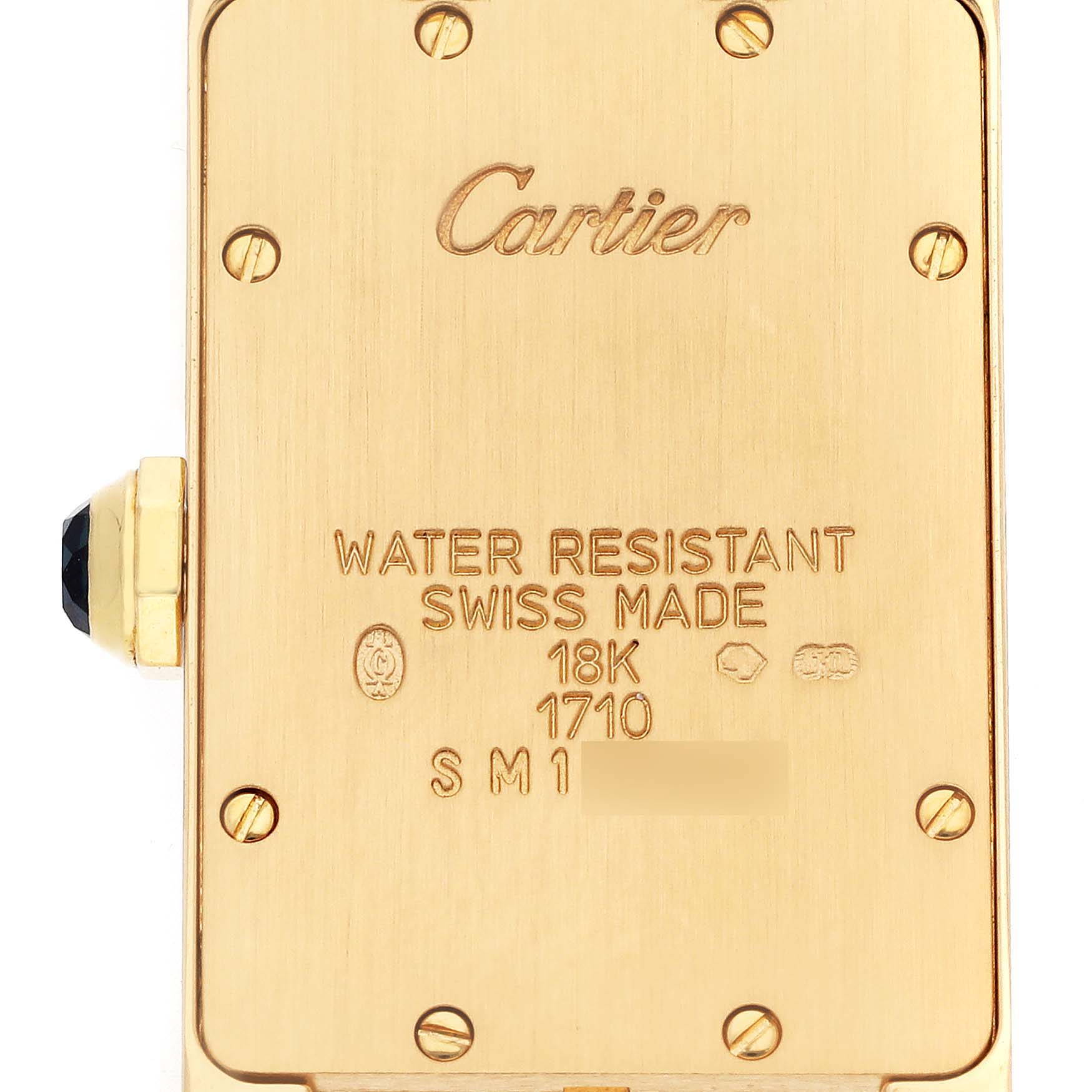 The Cartier Tank Américaine watch is shown from the back, highlighting its gold case, markings, and crown.