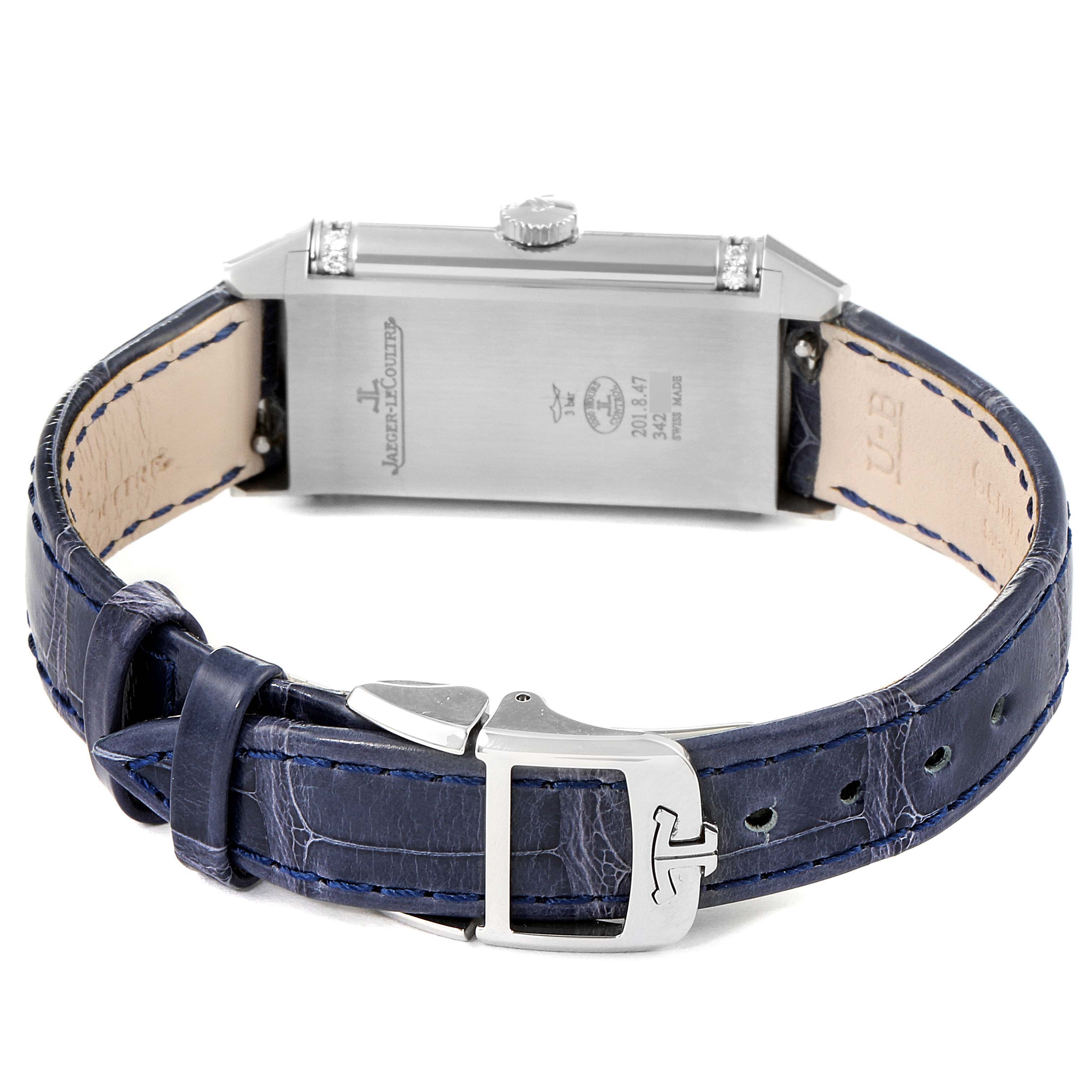 The image shows the back view of a Jaeger-LeCoultre Reverso watch, highlighting its stainless steel case, crown, and blue leather strap with a buckle.