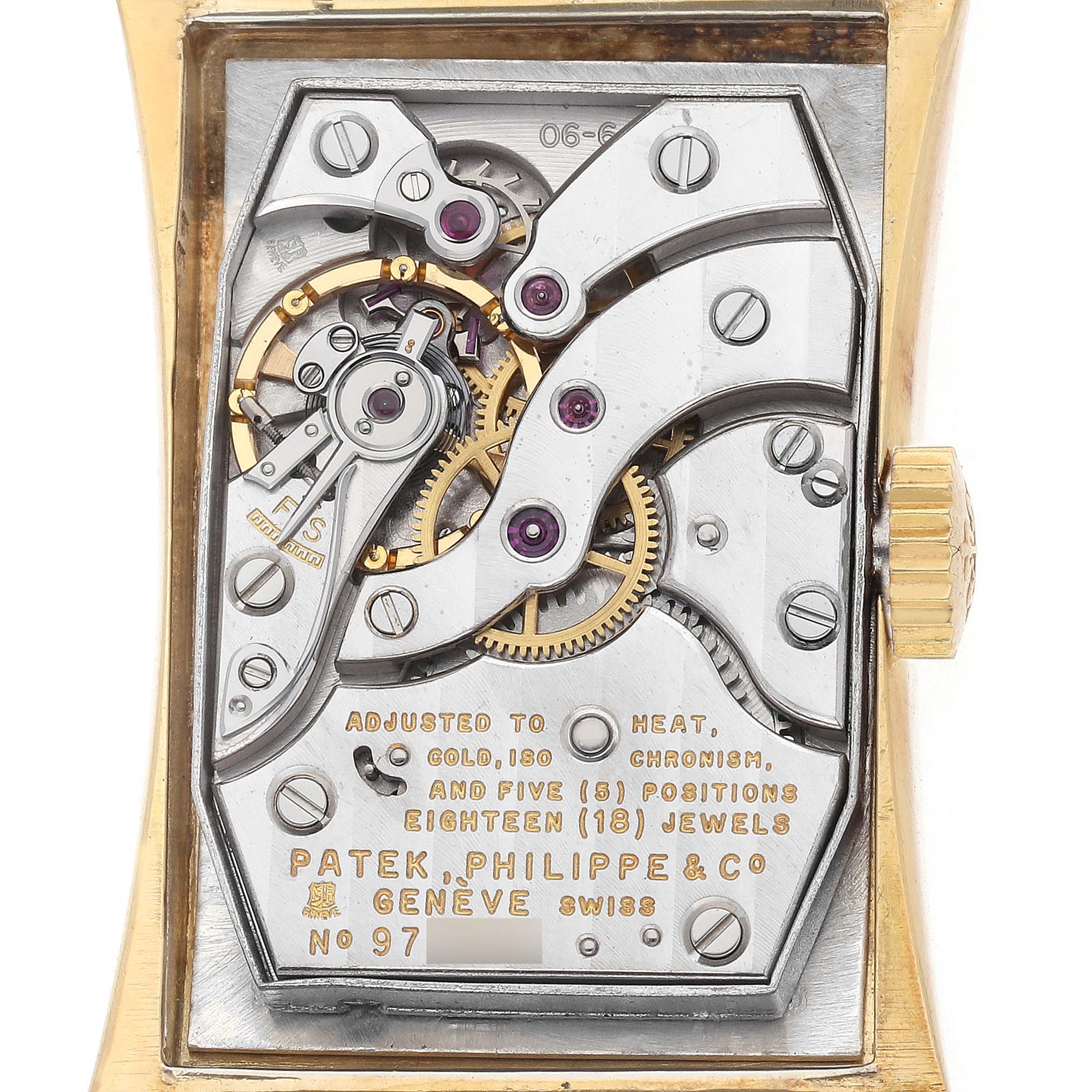 The image shows the movement of a vintage Patek Philippe watch from a back angle, highlighting gears and jewels.