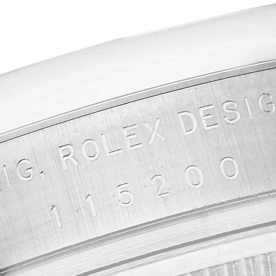 The image shows a close-up of the engraved model number on the side of a Rolex Date 115200 Men's Stainless Steel White Dial 115200 Men's Stainless Steel White Dial watch case.