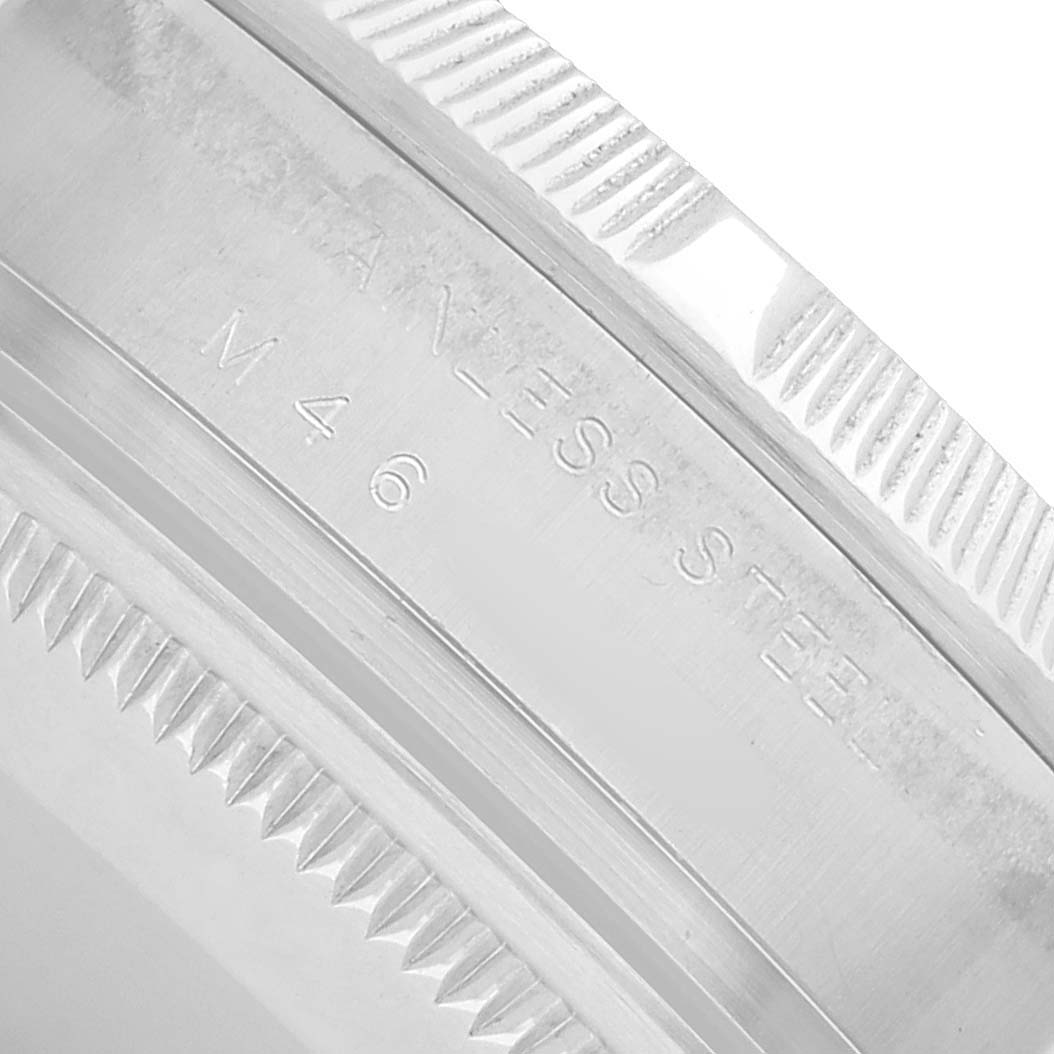 The image shows a close-up of the engraved stainless steel bezel of a Rolex Date 115210 Men's Stainless Steel White Dial model.