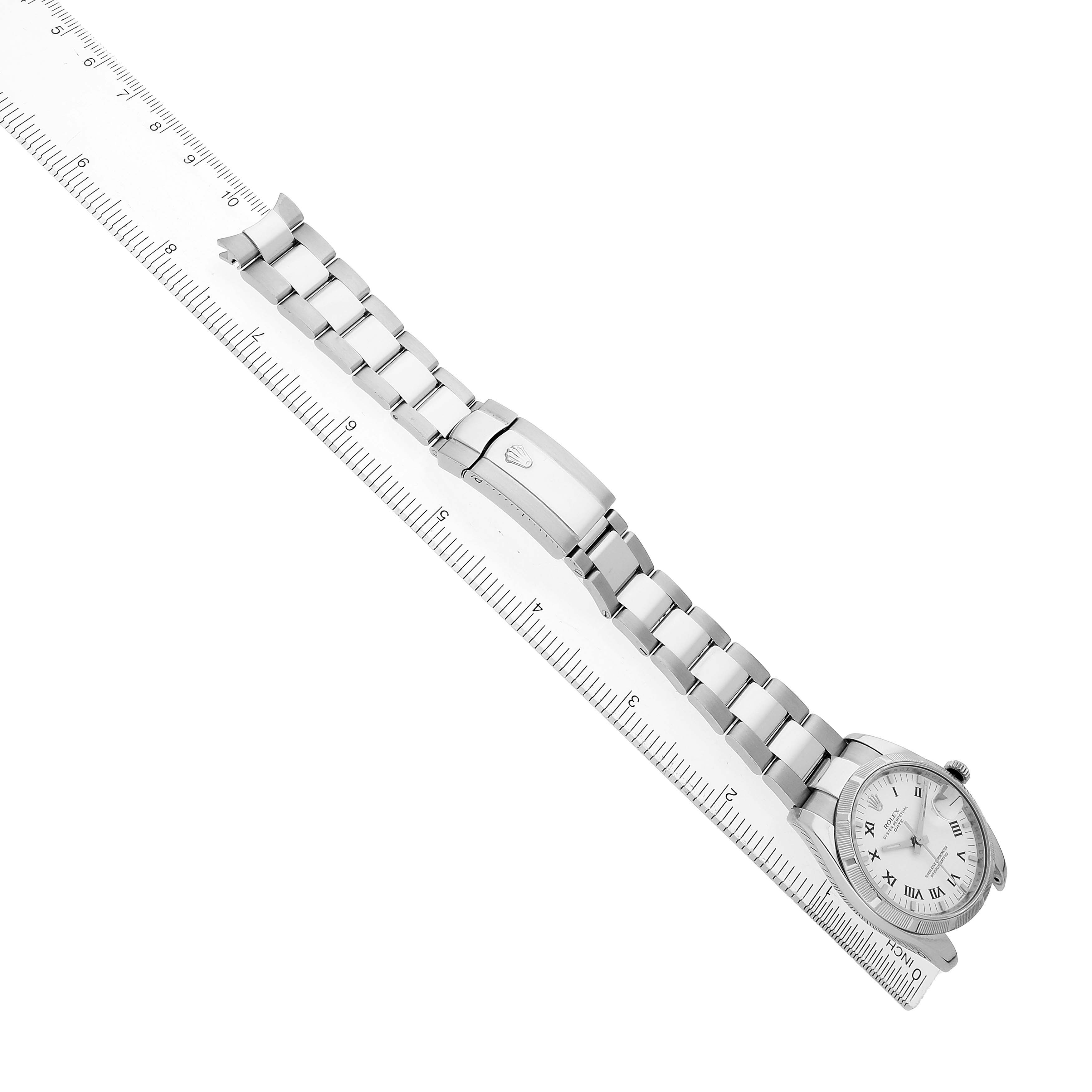 The Rolex Date 115210 Men's Stainless Steel White Dial watch is shown diagonally with its dial, bracelet, and clasp visible, alongside a ruler for scale.