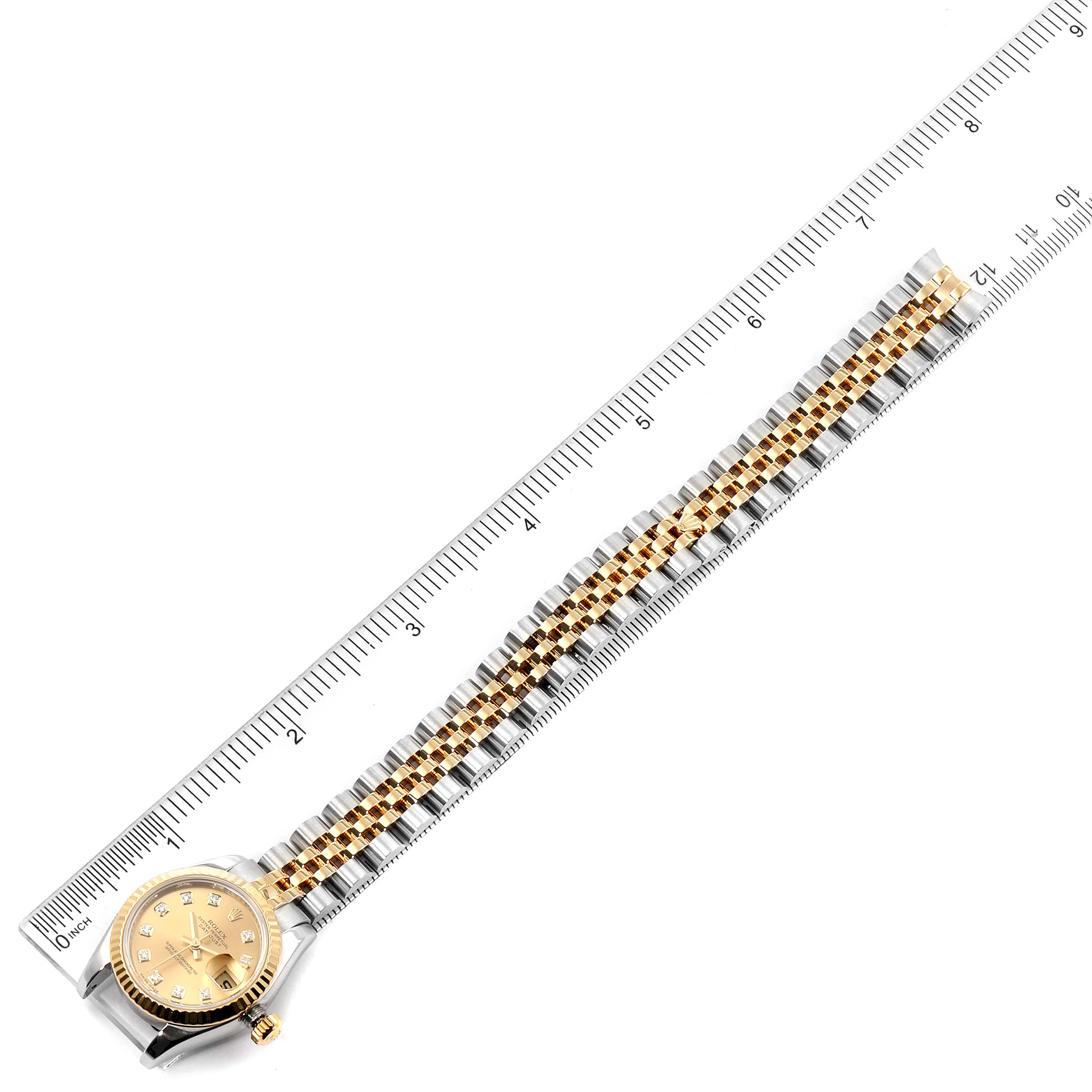 The image shows a top-down view of a Rolex Datejust 179173 Women
s Steel and Gold (two tone) Champagne Dial 179173 Women
s Steel and Gold (two tone) Champagne Dial watch with its band aligned along a ruler.