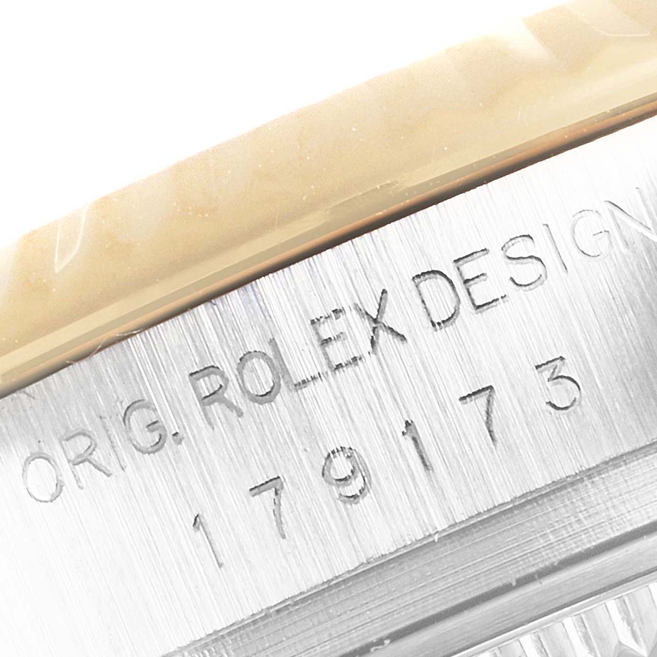 The image shows a close-up of the serial number and engravings, "ORIG. ROLEX DESIGN," on the side of a Rolex Datejust 179173 Women
s Steel and Gold (two tone) Champagne Dial 179173 Women
s Steel and Gold (two tone) Champagne Dial.