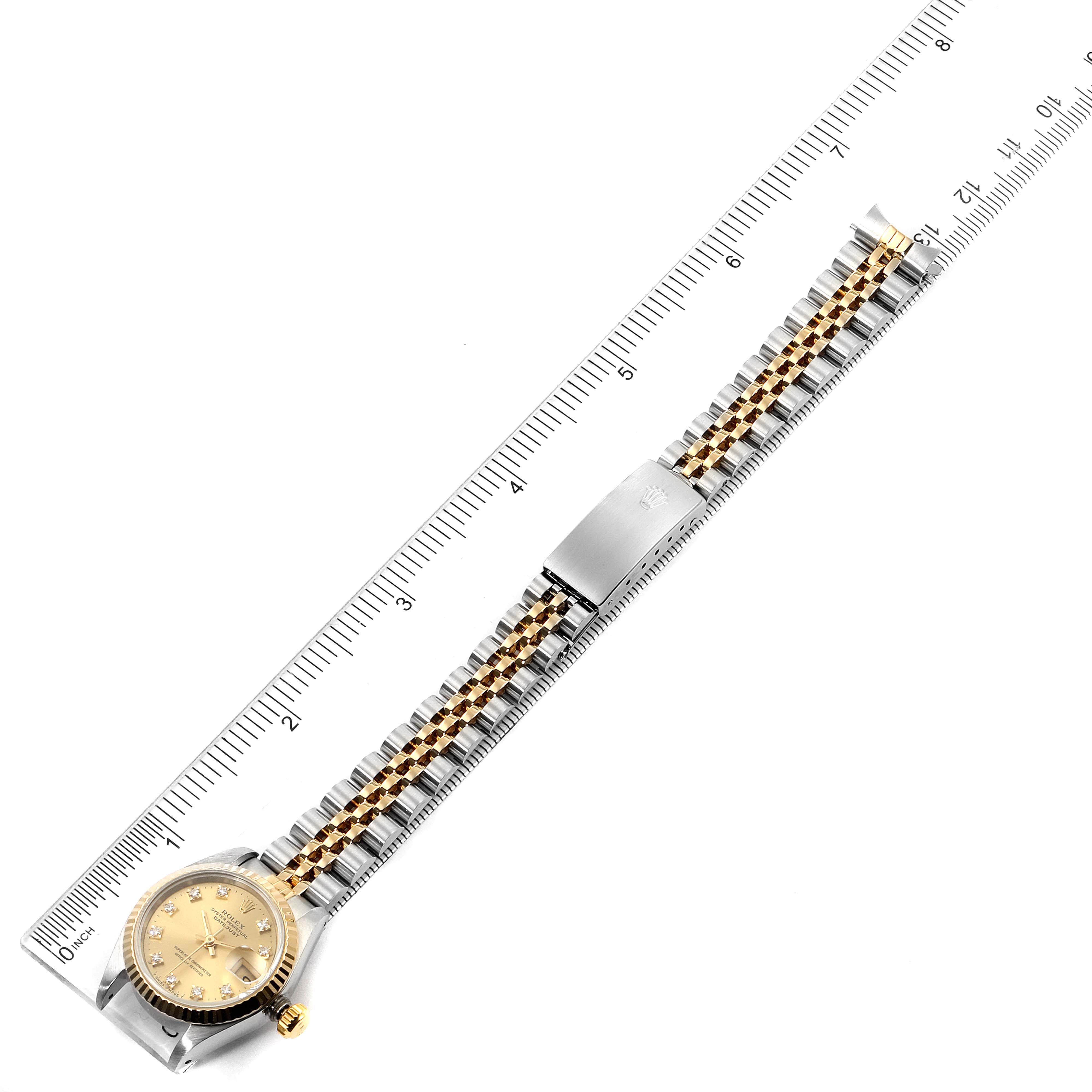 The image shows a top view of a Rolex Datejust 69173 Women
s Steel and Gold (two tone) Champagne Dial 69173 Women
s Steel and Gold (two tone) Champagne Dial watch with a ruler measuring the full length of the watch and band.