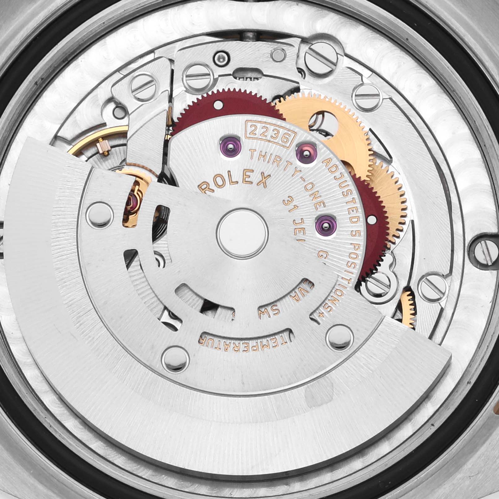 The image shows a close-up of the Rolex Datejust's movement, featuring gears and the rotor from a top-down angle.