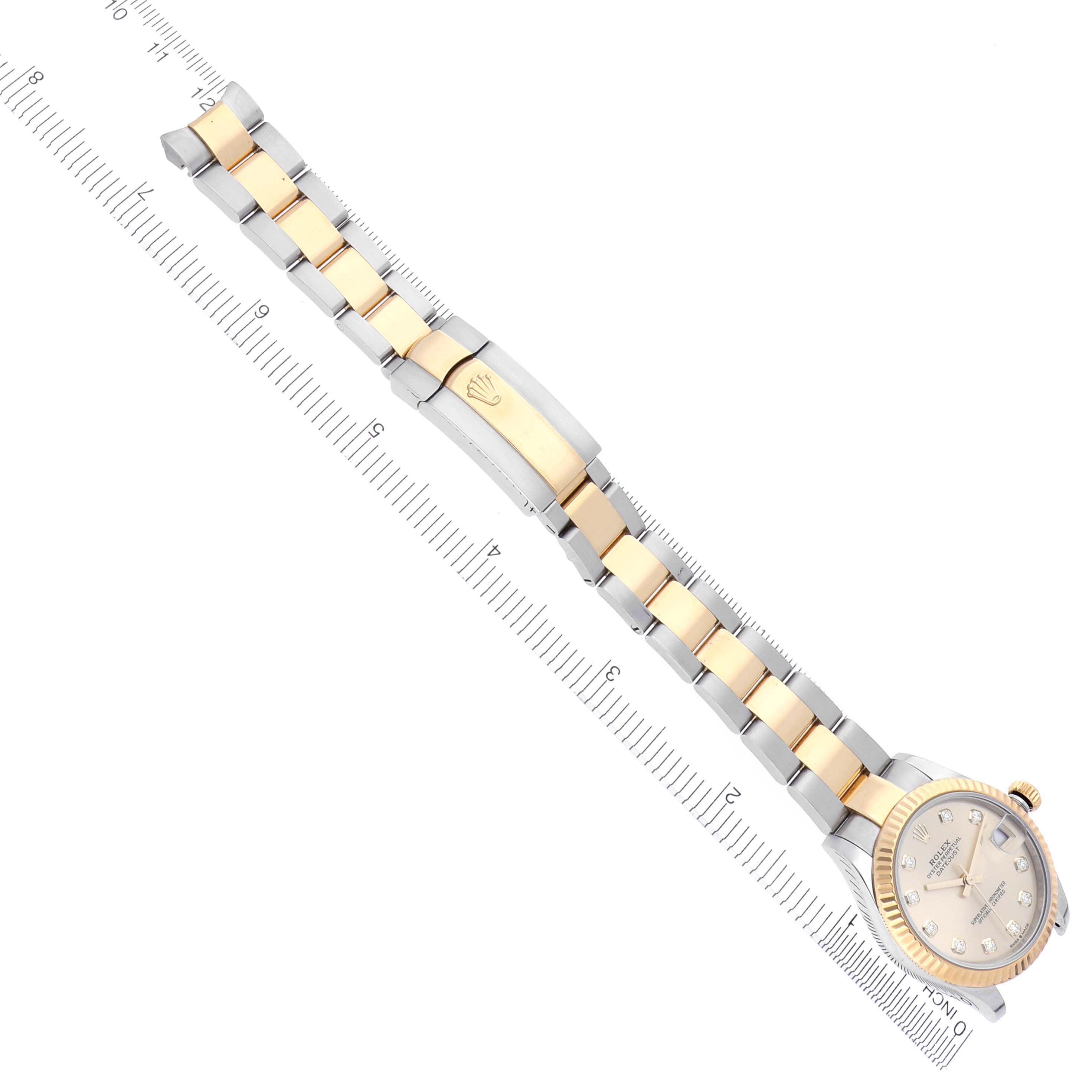 The Rolex Datejust watch is shown from an angled top view, highlighting the bracelet and clasp alongside a ruler.