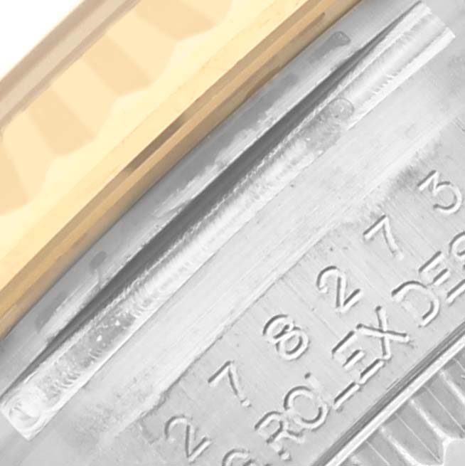 The image shows a close-up of the side engraving and fluted bezel of a Rolex Datejust watch.