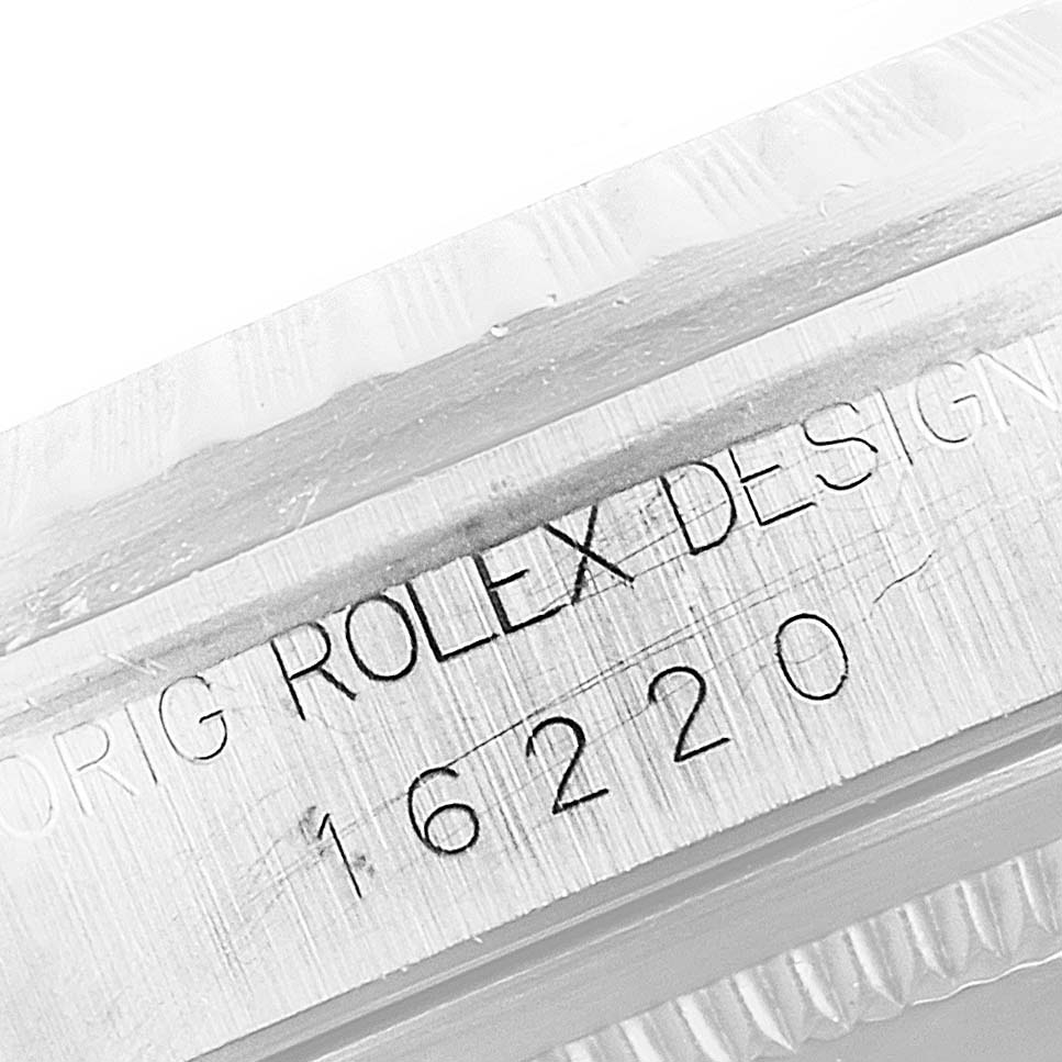 This close-up shot of a Rolex Datejust 16220 Men's Stainless Steel Silver Dial 16220 Men's Stainless Steel Silver Dial watch displays the model number "16220" and the engraving "ORIG ROLEX DESIGN."