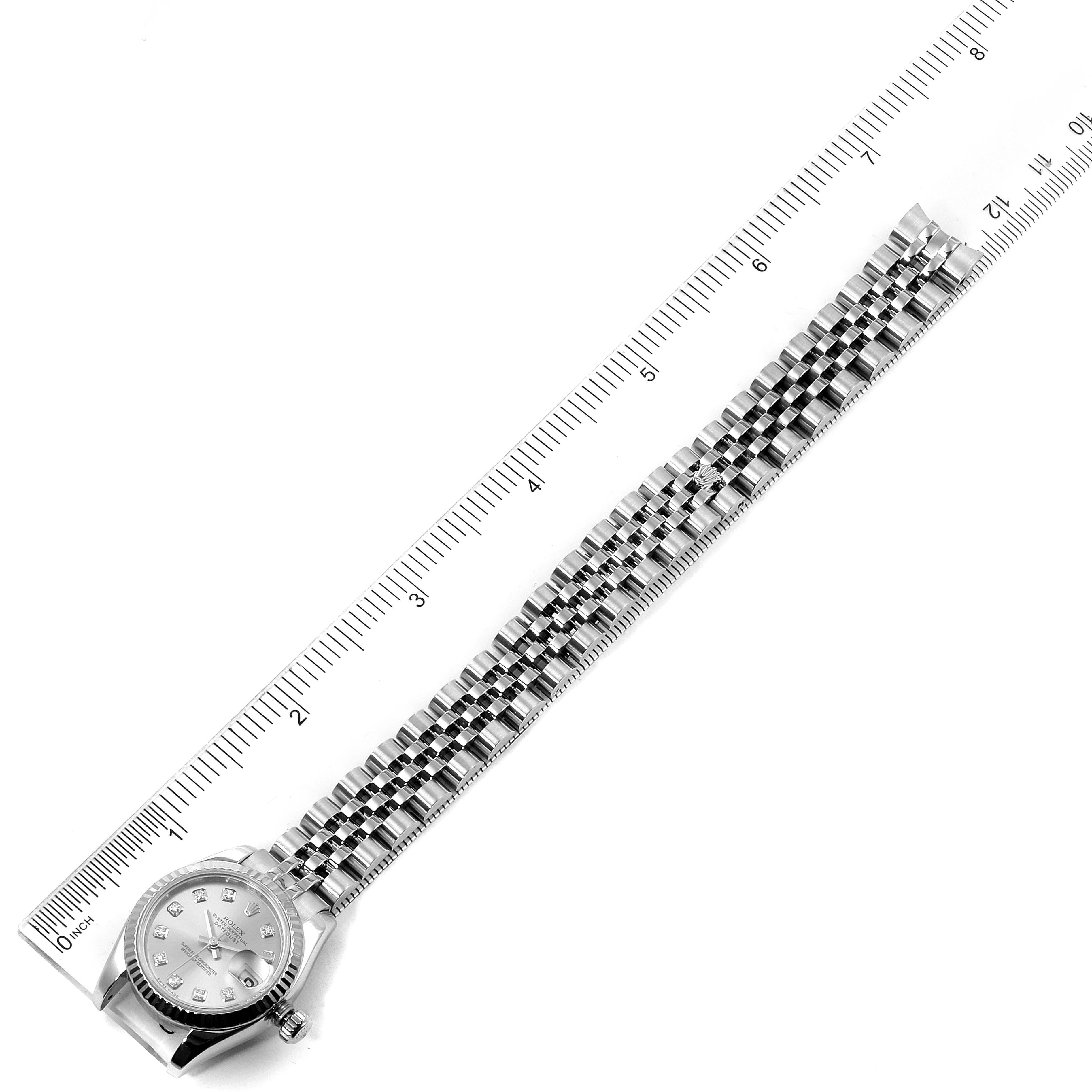 The image shows a top-down view of the Rolex Datejust 179174 Women
s Stainless Steel Silver Dial 179174 Women
s Stainless Steel Silver Dial watch displaying its dial and full bracelet alongside a ruler.