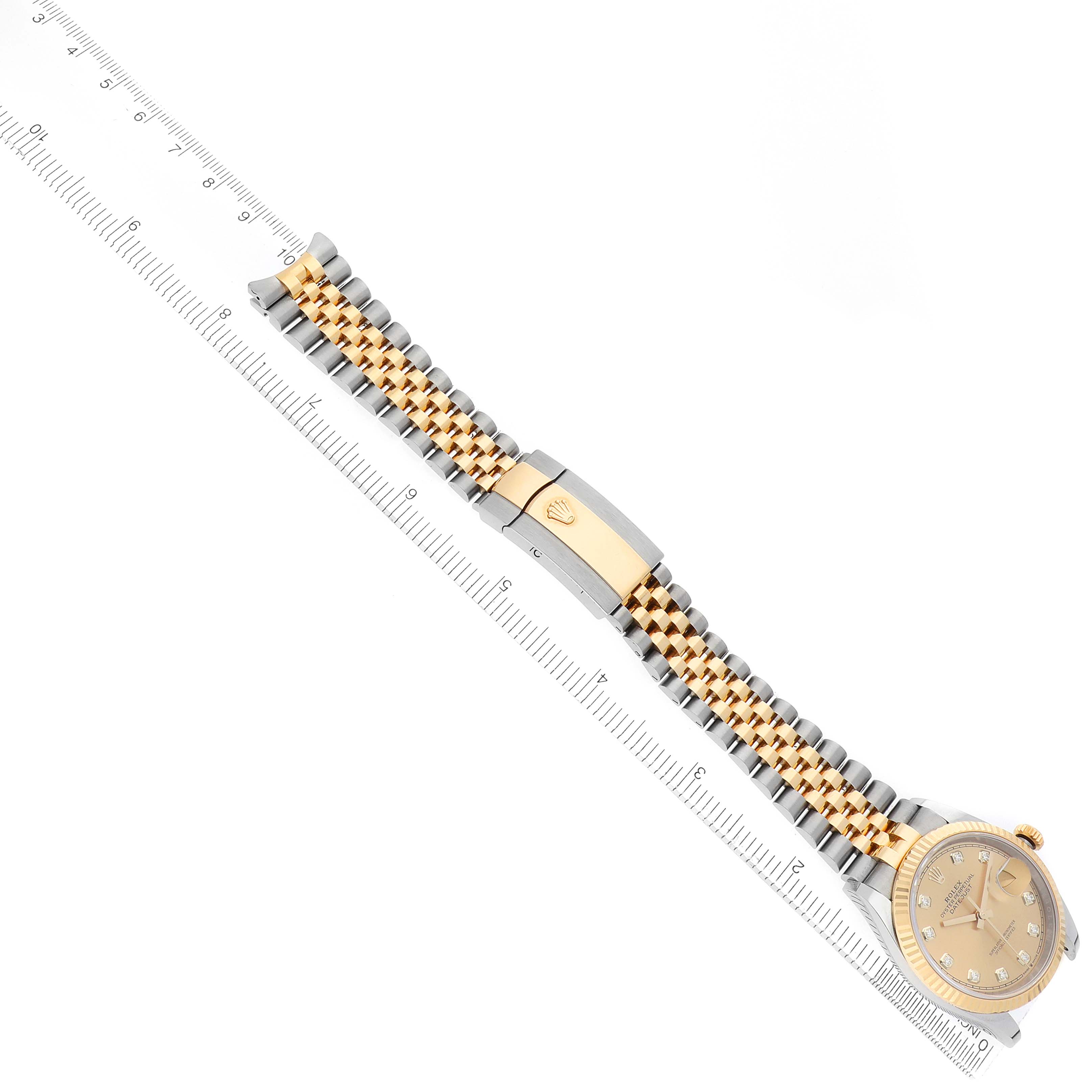 The image shows a Rolex Datejust 126233 Men's Steel and Gold (two tone) Champagne Dial watch laid flat, featuring a gold and silver bracelet, clasp, and a visible face with a ruler for scale.