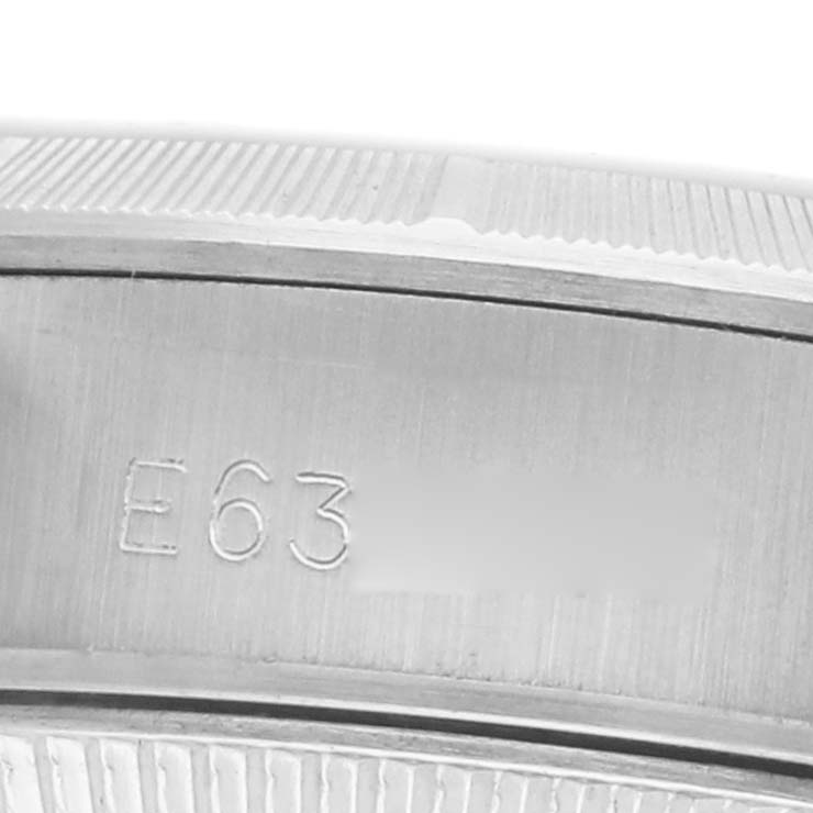 The image shows a close-up of the side of a Rolex Oyster Perpetual 67230 Women's Stainless Steel Silver Dial watch, displaying part of the engraved serial number.