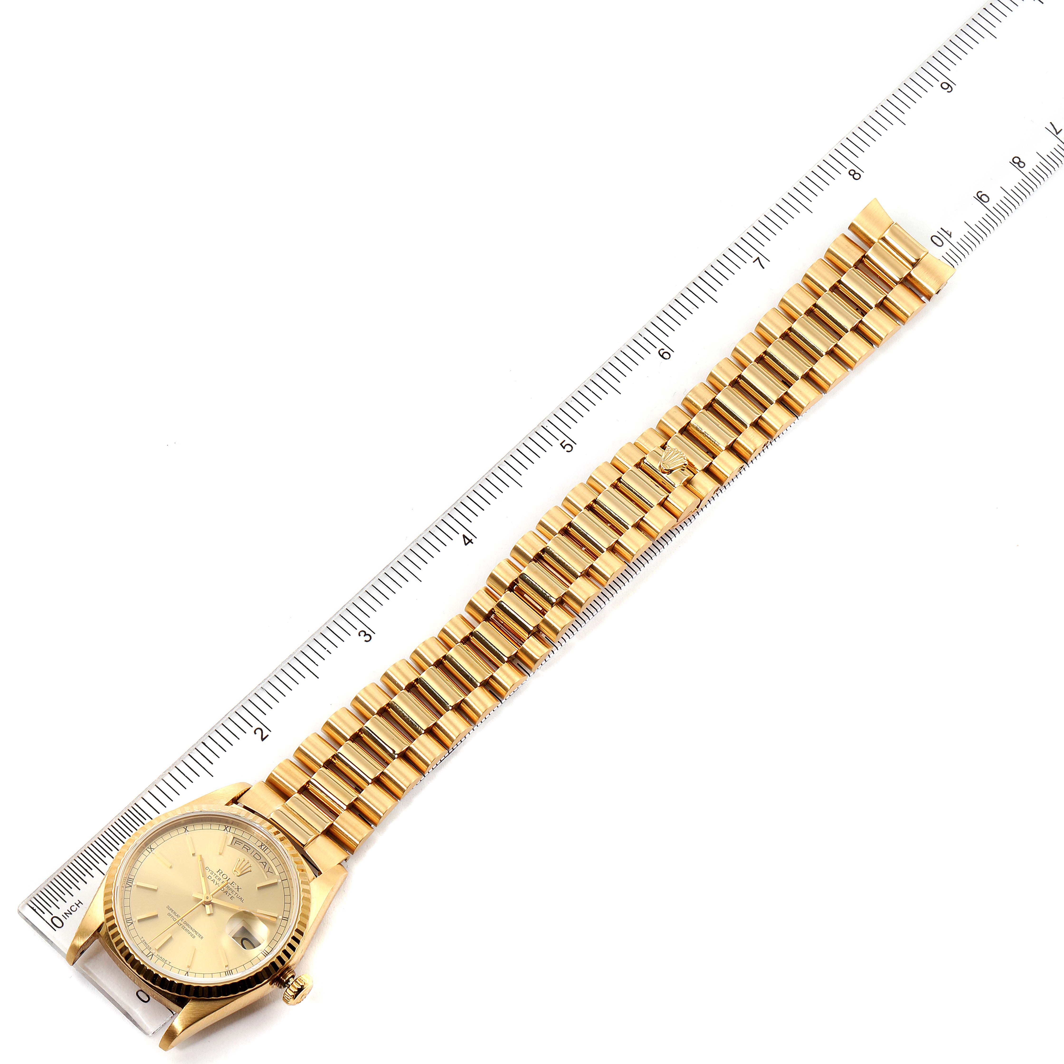 The Rolex President 18238 Men
s Yellow Gold Champagne Dial 18238 Men
s Yellow Gold Champagne Dial model watch is shown from a top-down angle, displaying its full band beside a marked ruler.