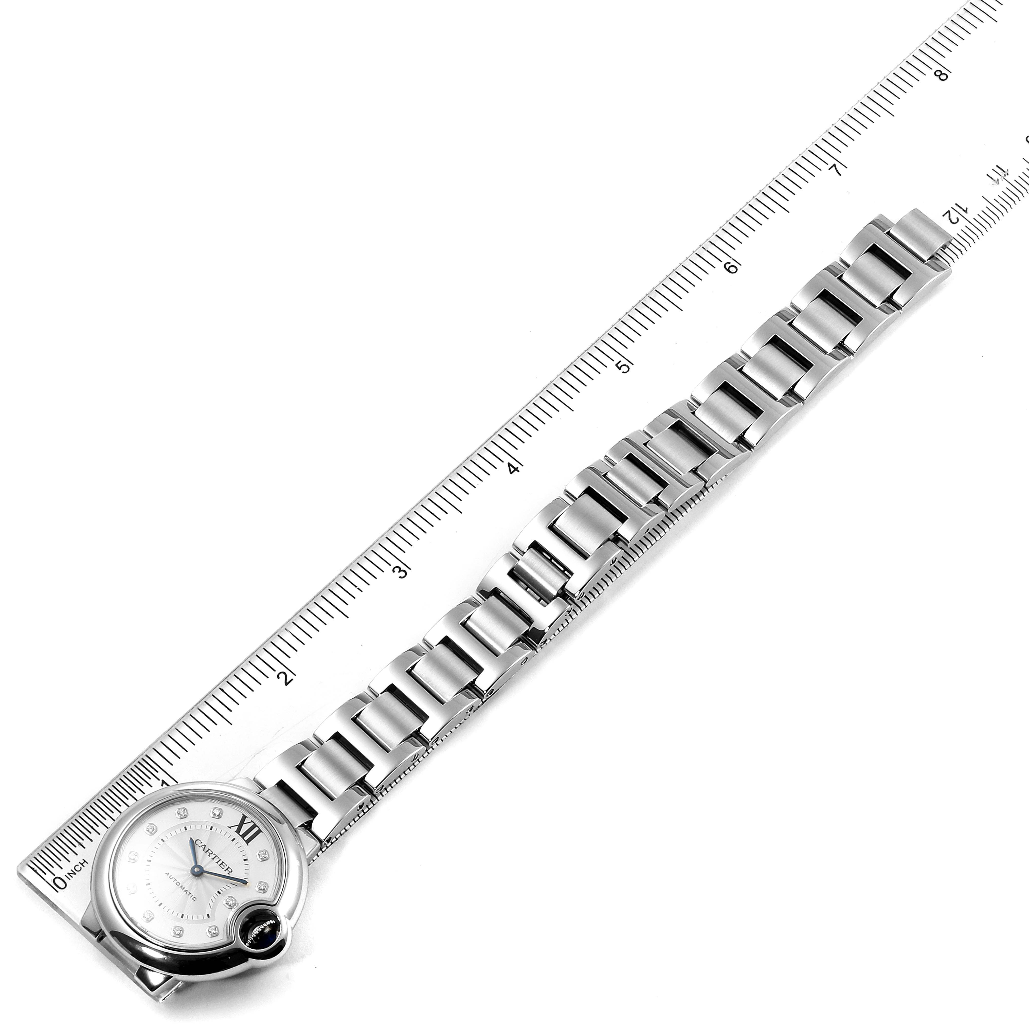 This image shows a top view of the Ballon Bleu watch by Cartier, displaying its face, case, and stainless steel bracelet alongside a ruler for measurement.