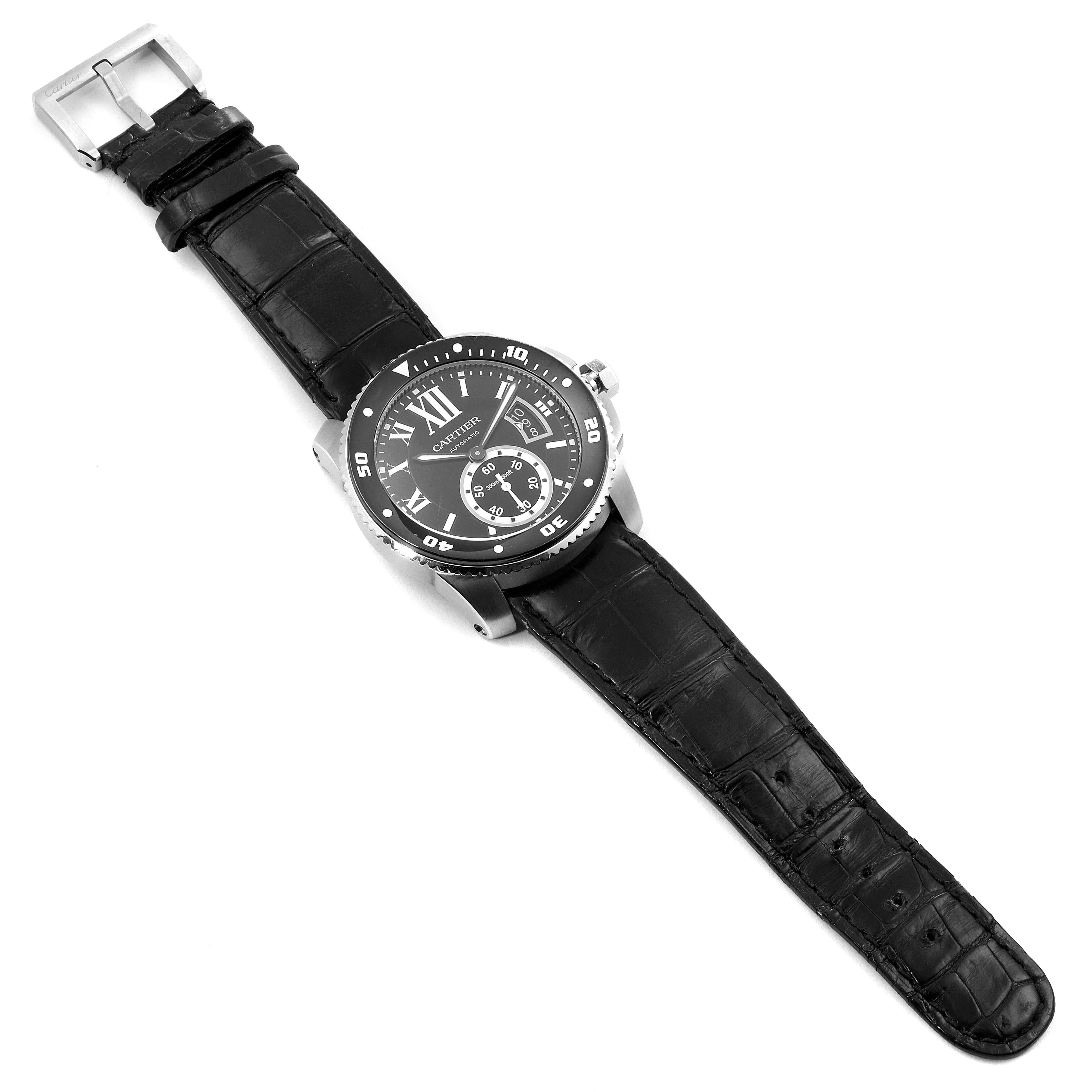 The image shows a Calibre de Cartier watch by Cartier, featuring a black strap and round face, viewed from an angled top-down perspective.