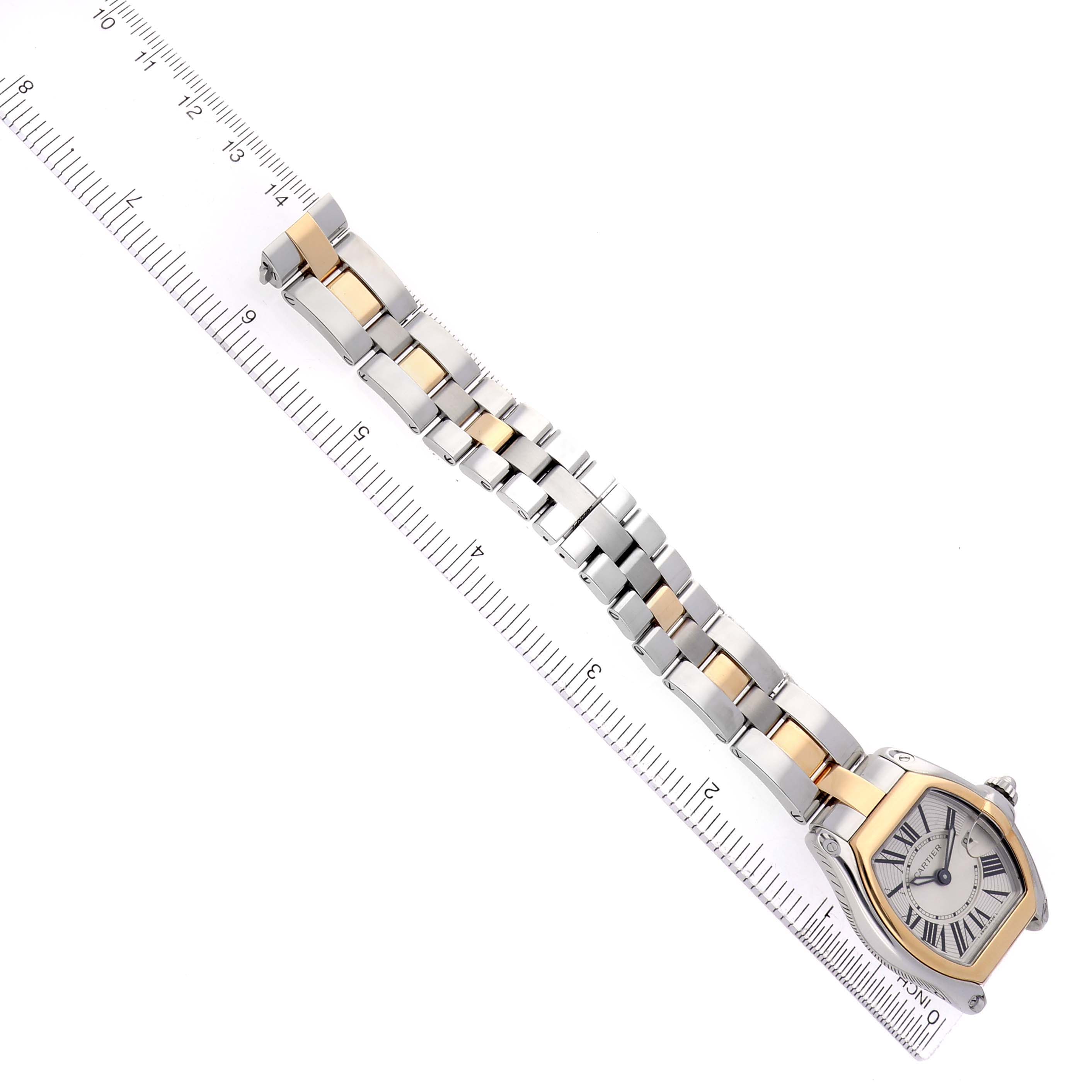 The Cartier Roadster W62026Y4 Women's Steel and Gold (two tone) Silver Dial watch is shown at an angle, highlighting its face and bracelet, placed on a measuring ruler.