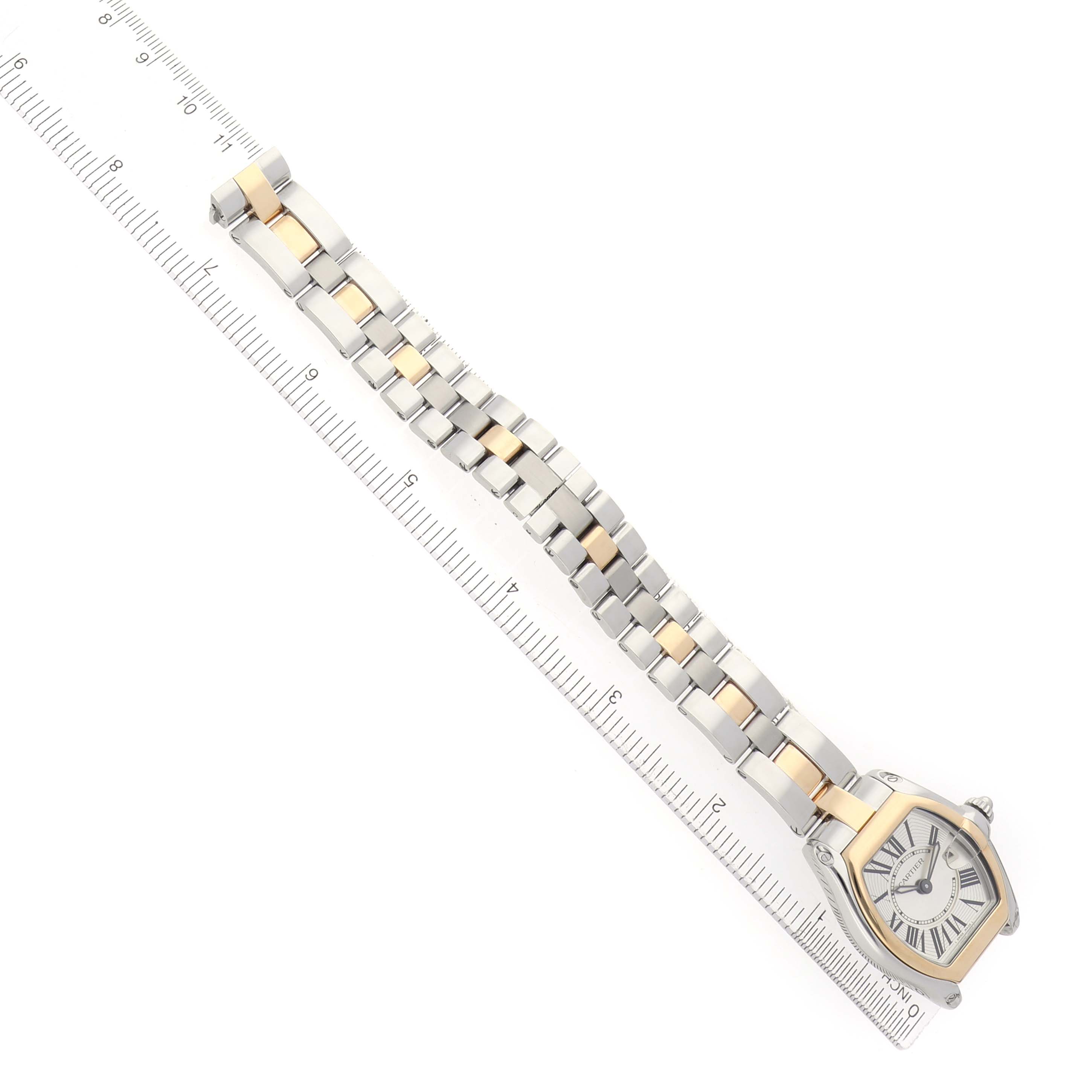 The Cartier Roadster W62026Y4 Women's Steel and Gold (two tone) Silver Dial watch is shown diagonally with the face, bezel, and full bracelet visible alongside a ruler.