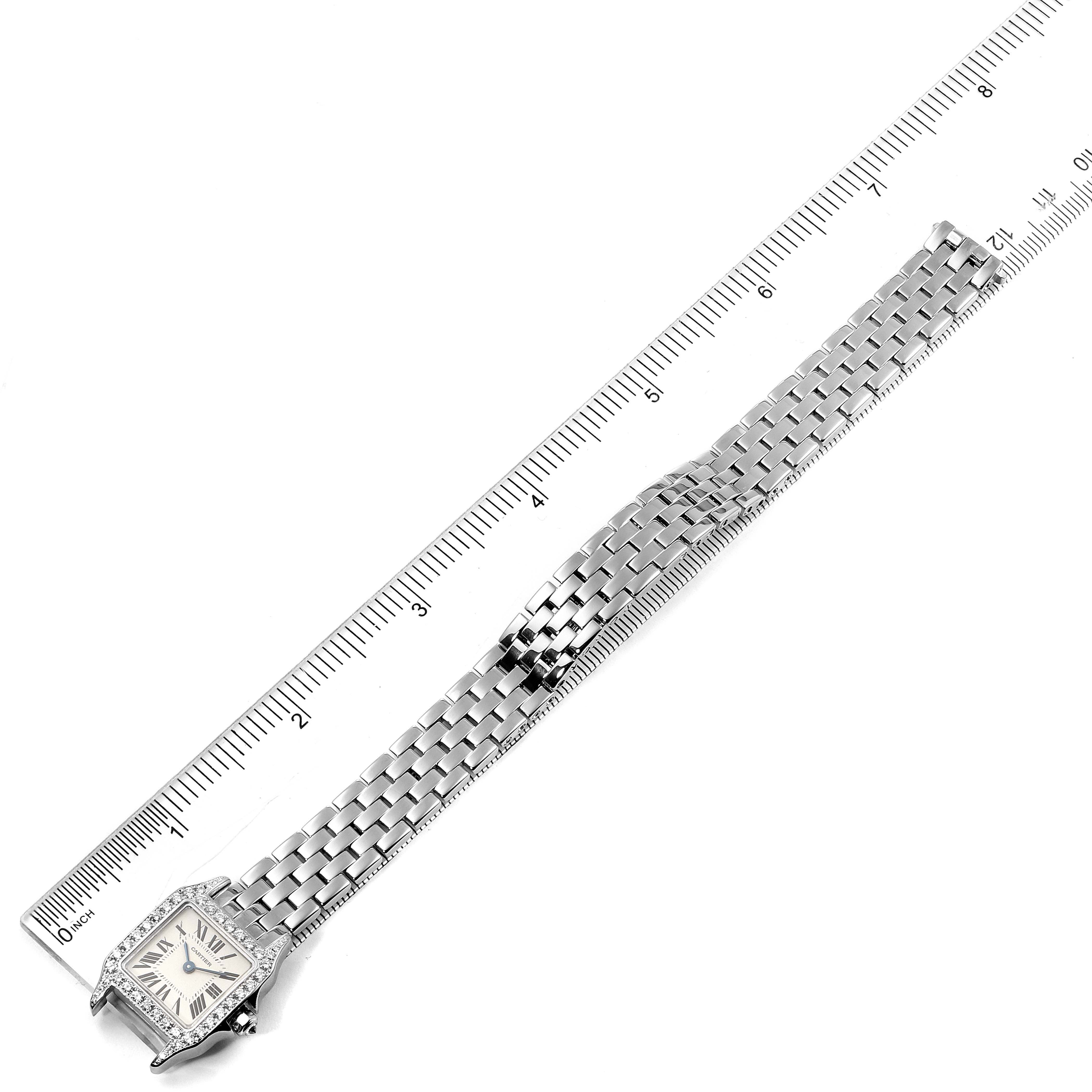 The image shows a top-down view of the Cartier Santos Demoiselle WF9005Y8 Women's White Gold Silver Dial WF9005Y8 Women's White Gold Silver Dial watch with its metal bracelet alongside a ruler.
