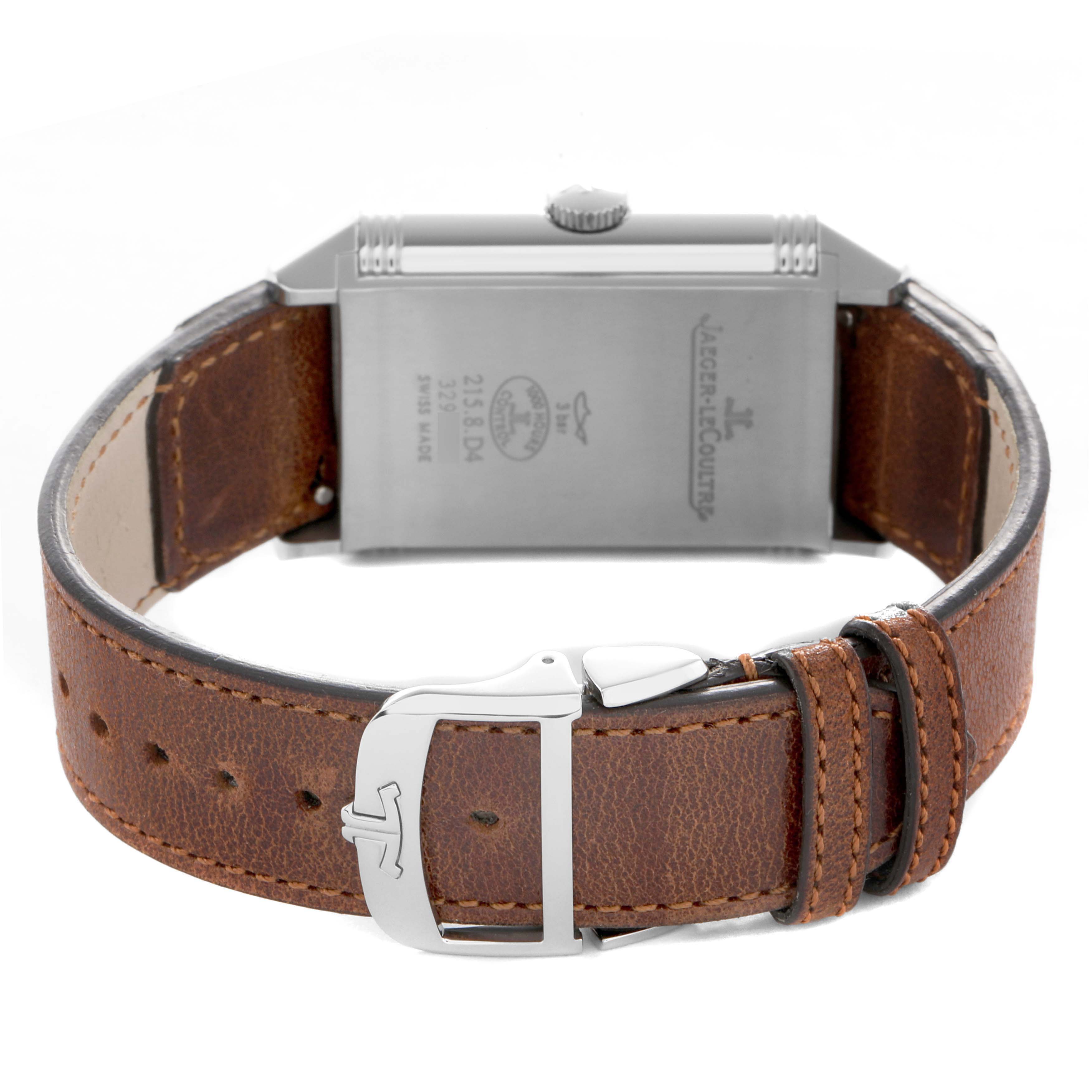 The Jaeger-LeCoultre Reverso watch is shown from the back, displaying the case back, crown, and brown leather strap with buckle.