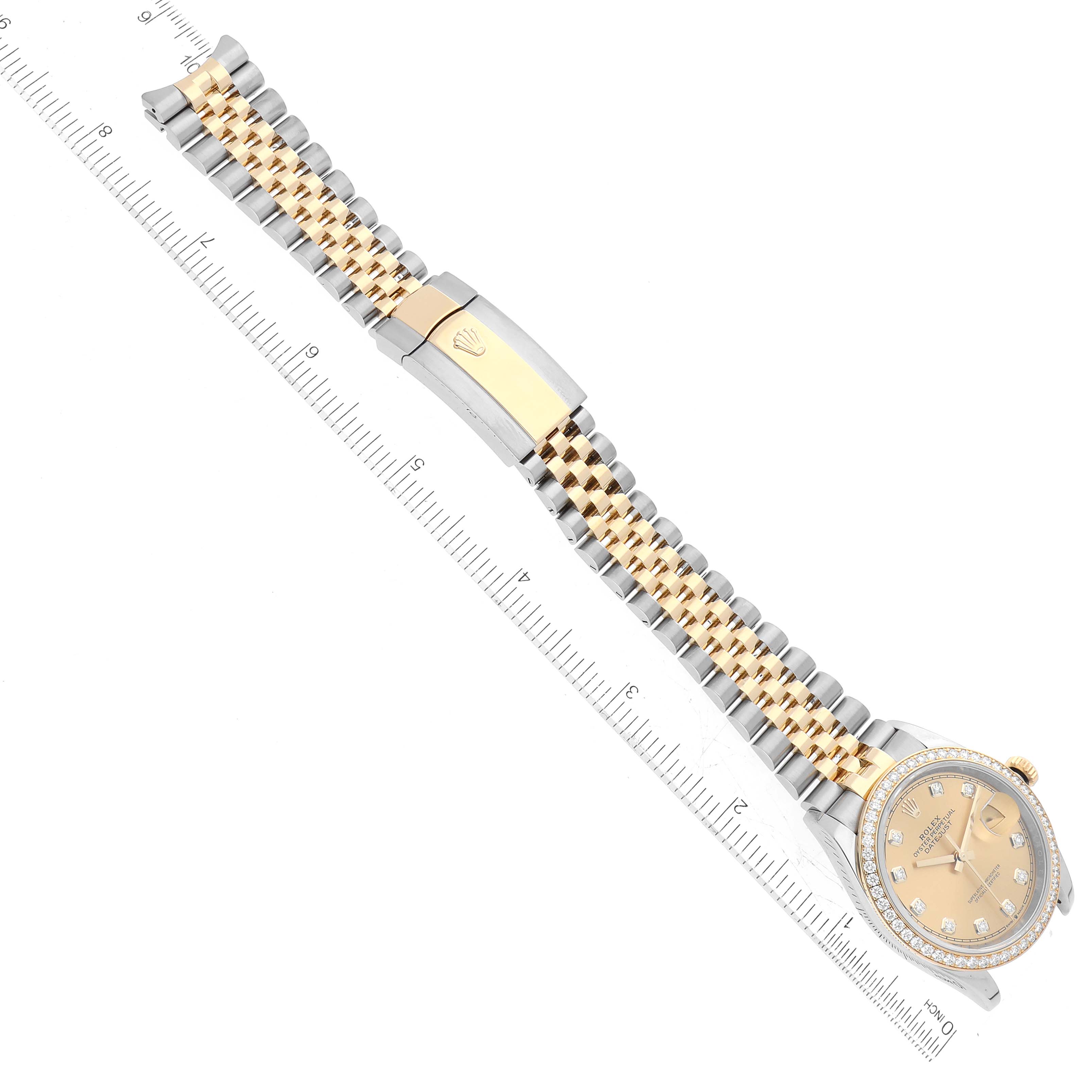 The image shows an overhead view of a Rolex Datejust 126283RBR Men's Steel and Gold (two tone) Champagne Dial 126283RBR Men's Steel and Gold (two tone) Champagne Dial watch, highlighting its bracelet and partially visible face with a ruler for scale.