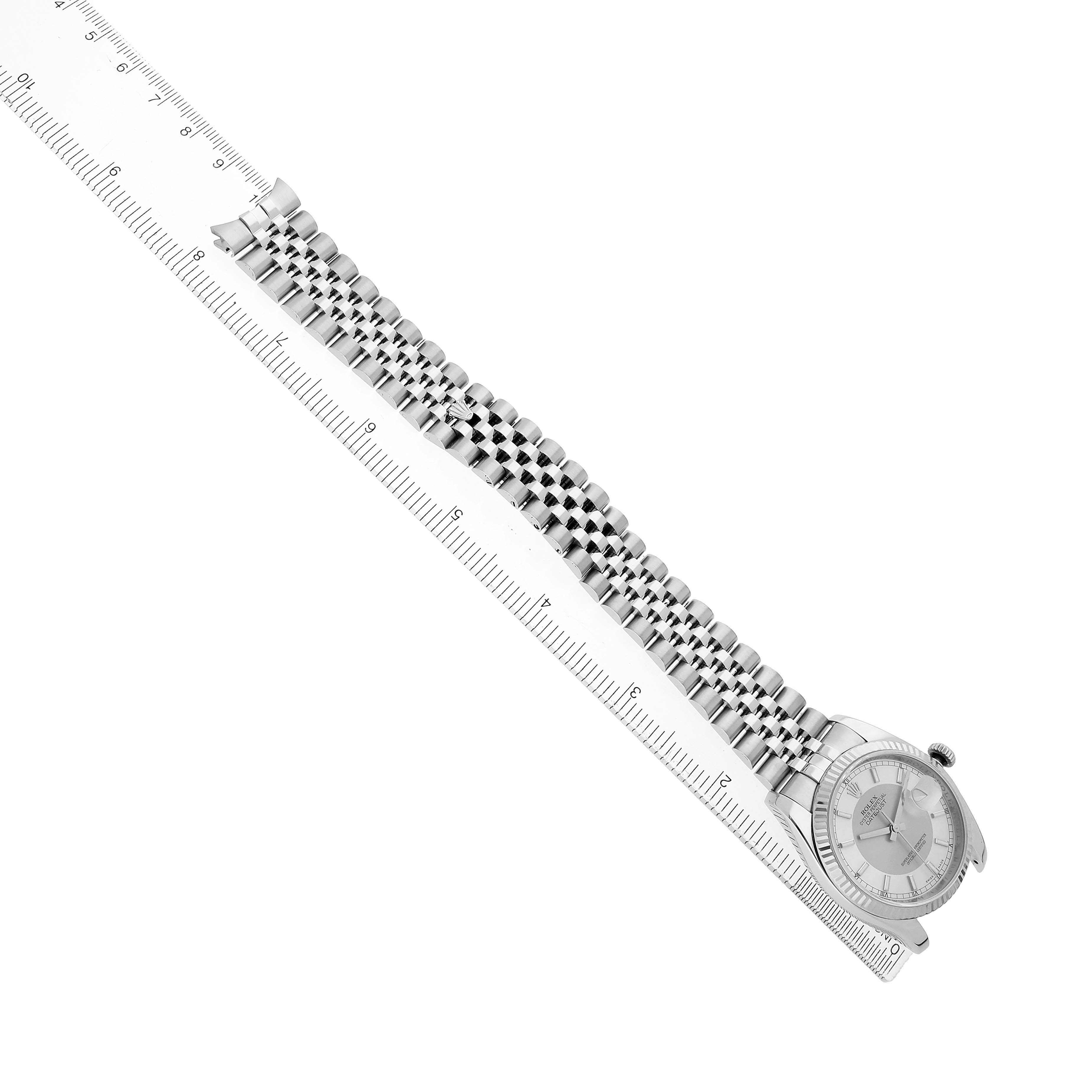 The image shows a Rolex Datejust 116234 Men's Stainless Steel Silver Dial watch at a diagonal angle, displaying the dial and bracelet alongside a ruler.