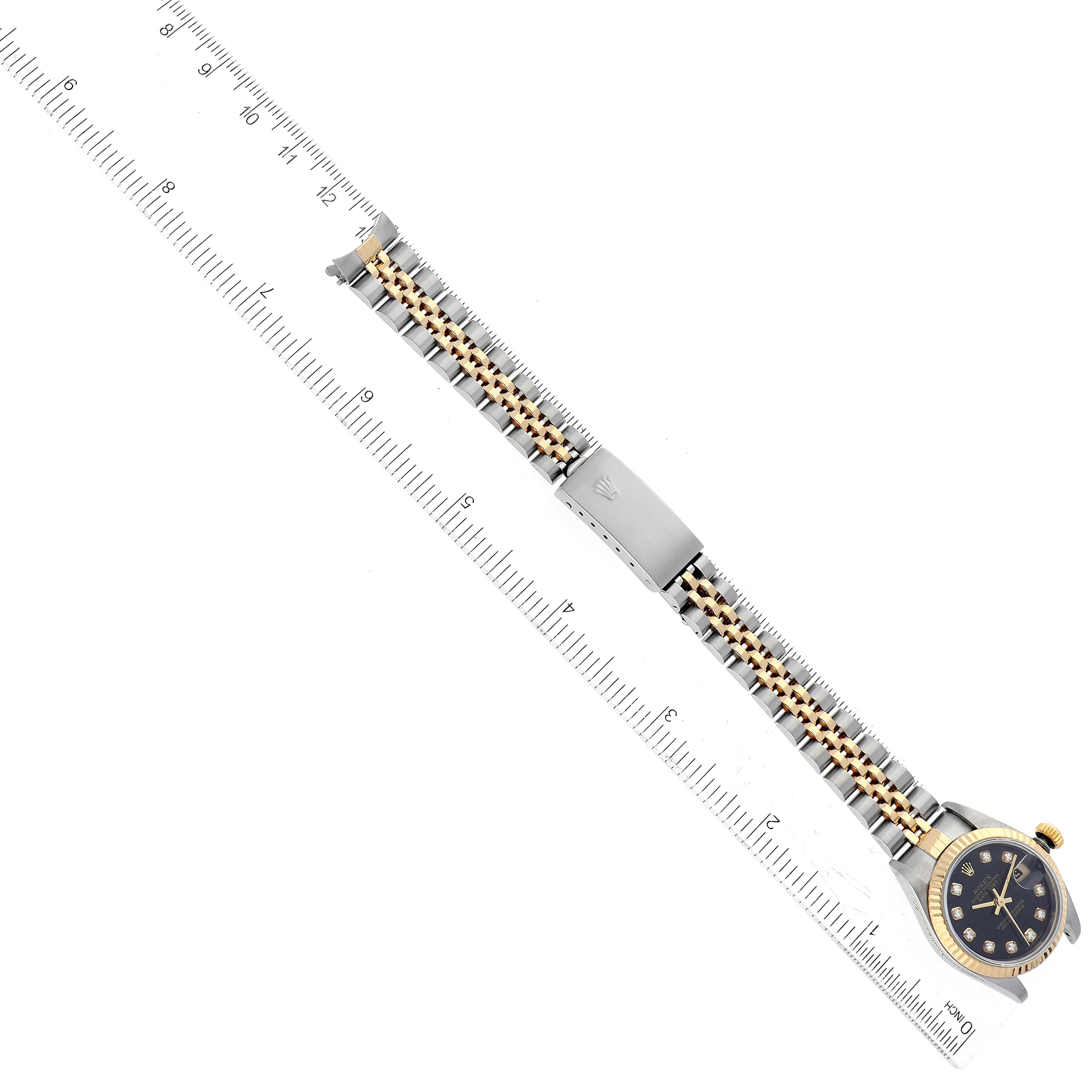 The image shows a top view of a Rolex Datejust 79173 Women's Steel and Gold (two tone) Black Dial 79173 Women's Steel and Gold (two tone) Black Dial watch, highlighting its face, bezel, and full bracelet, with a ruler for scale.