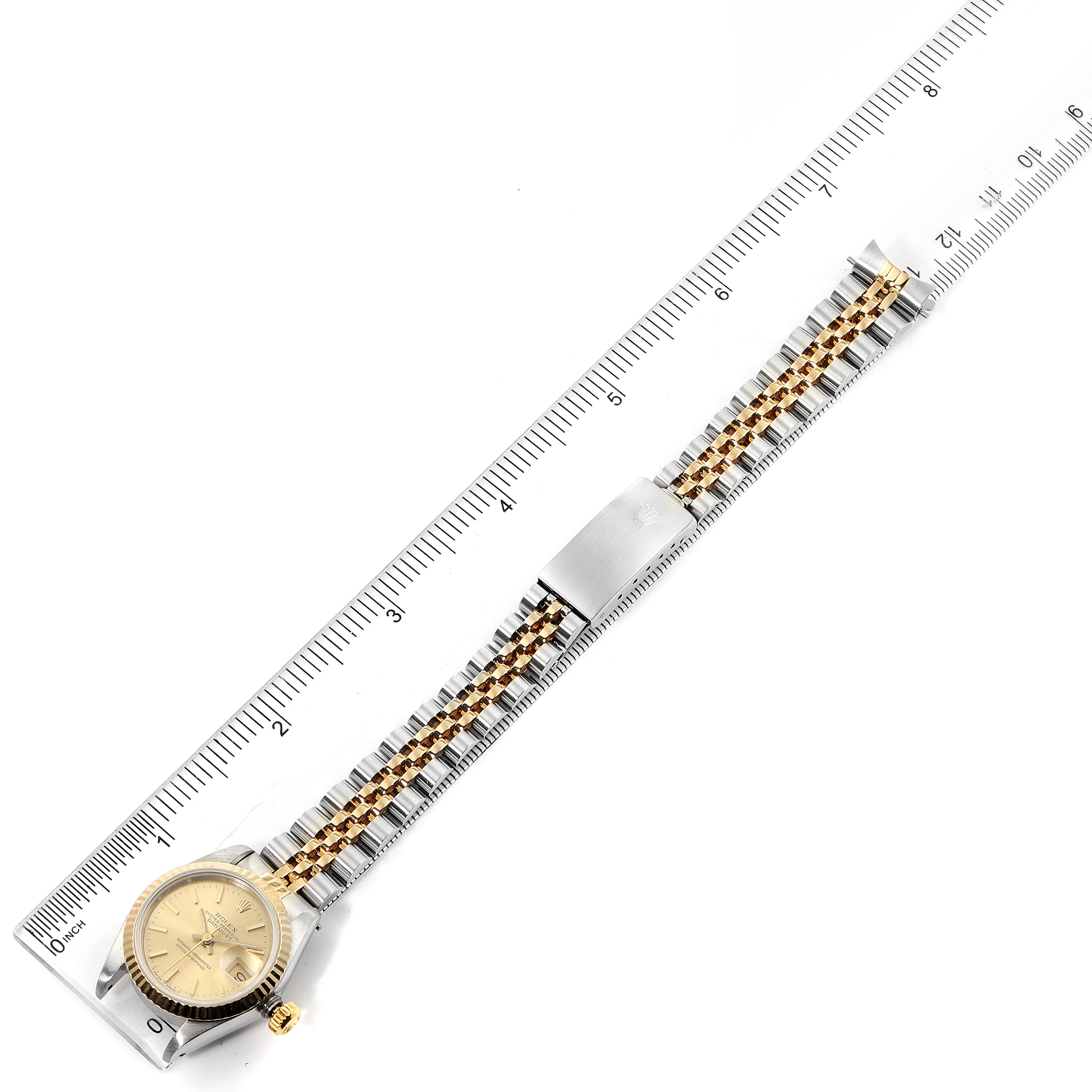 This overhead shot shows the full Rolex Datejust 69173 Women's Steel and Gold (two tone) Champagne Dial 69173 Women's Steel and Gold (two tone) Champagne Dial watch, featuring its face, bezel, bracelet, and clasp, alongside a measuring ruler.