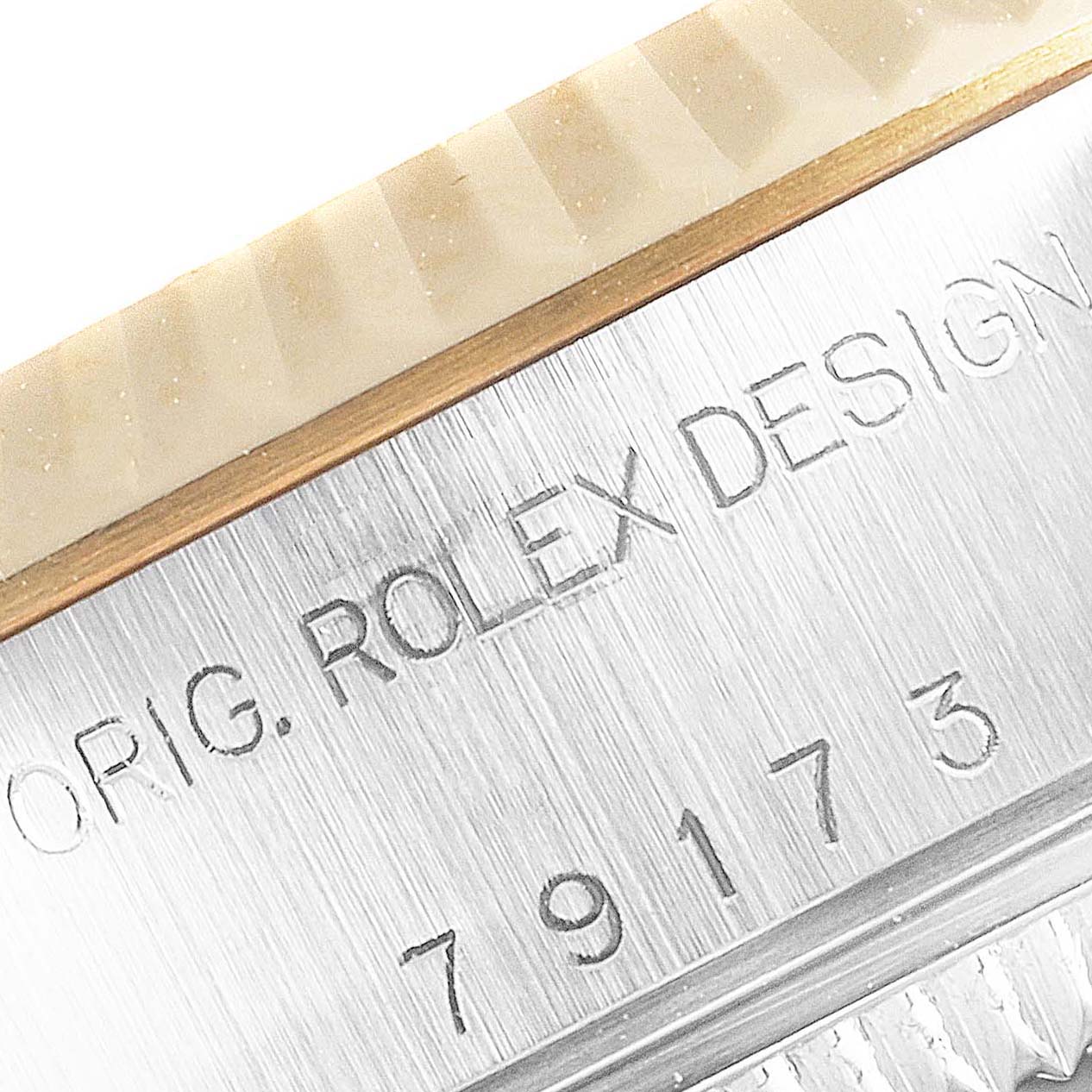 The image shows a close-up of the engraved case back of a Rolex Datejust 79173 Women
s Steel and Gold (two tone) Silver Dial 79173 Women
s Steel and Gold (two tone) Silver Dial, revealing part of the serial number and "ROLEX DESIGN".