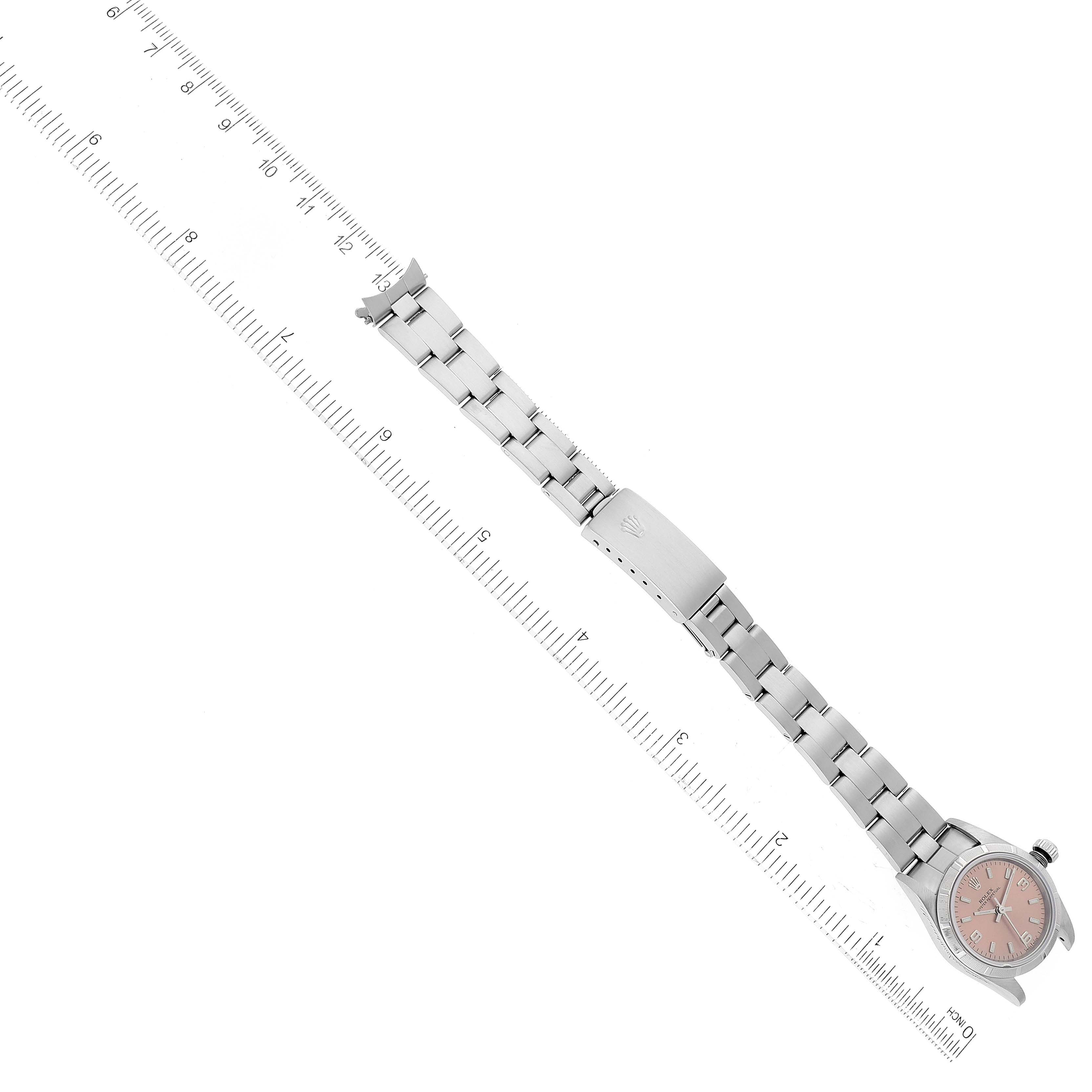 The image shows a Rolex Oyster Perpetual 76030 Women
s Stainless Steel Pink Dial 76030 Women
s Stainless Steel Pink Dial watch, displayed flat with the full length of the bracelet and clasp visible, alongside a ruler for scale.