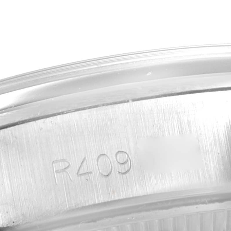 This image shows a close-up of the side of the case back of a Rolex Oyster Perpetual 67230 Women's Stainless Steel Silver Dial 67230 Women's Stainless Steel Silver Dial watch, displaying part of its serial number.