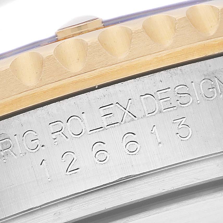 This image shows a close-up of the engraved side of a Rolex Submariner 126613LB Men's Steel and Gold (two tone) Blue Dial 126613LB Men's Steel and Gold (two tone) Blue Dial model, featuring part of the bezel and case.
