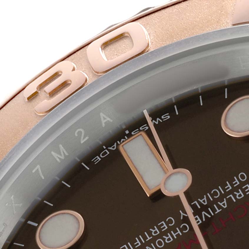 The image shows a close-up of the Rolex Yacht-Master 116621 Men's Steel and Gold (two tone) Brown Dial's bezel, part of the dial, and a hand, angled to highlight details.