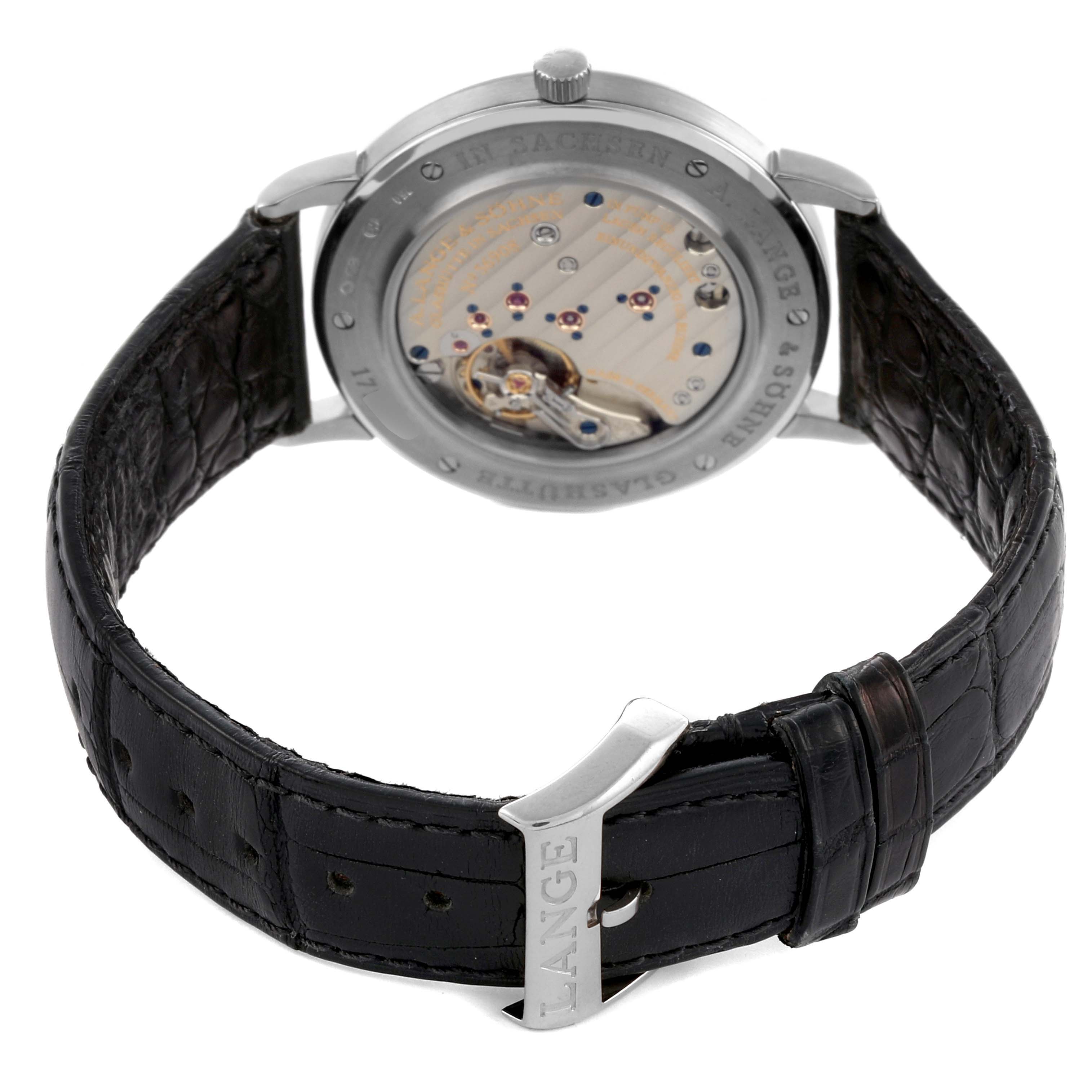 The image shows the back view of the A. Lange & Sohne Saxonia 215.029 Men's White Gold Black Dial watch, highlighting the movement and black leather strap with a buckle.