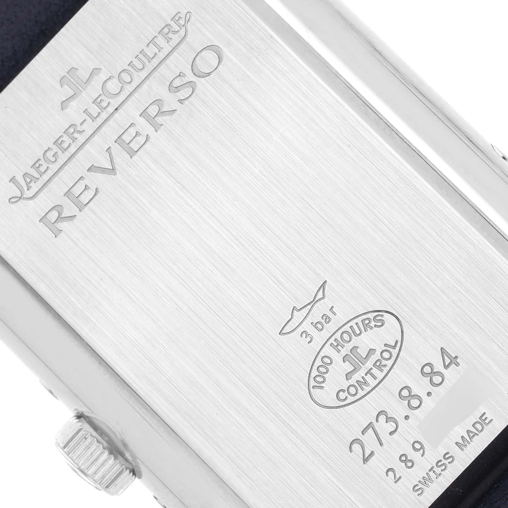 The image shows the back of a Jaeger-LeCoultre Reverso watch, highlighting engravings and the crown.