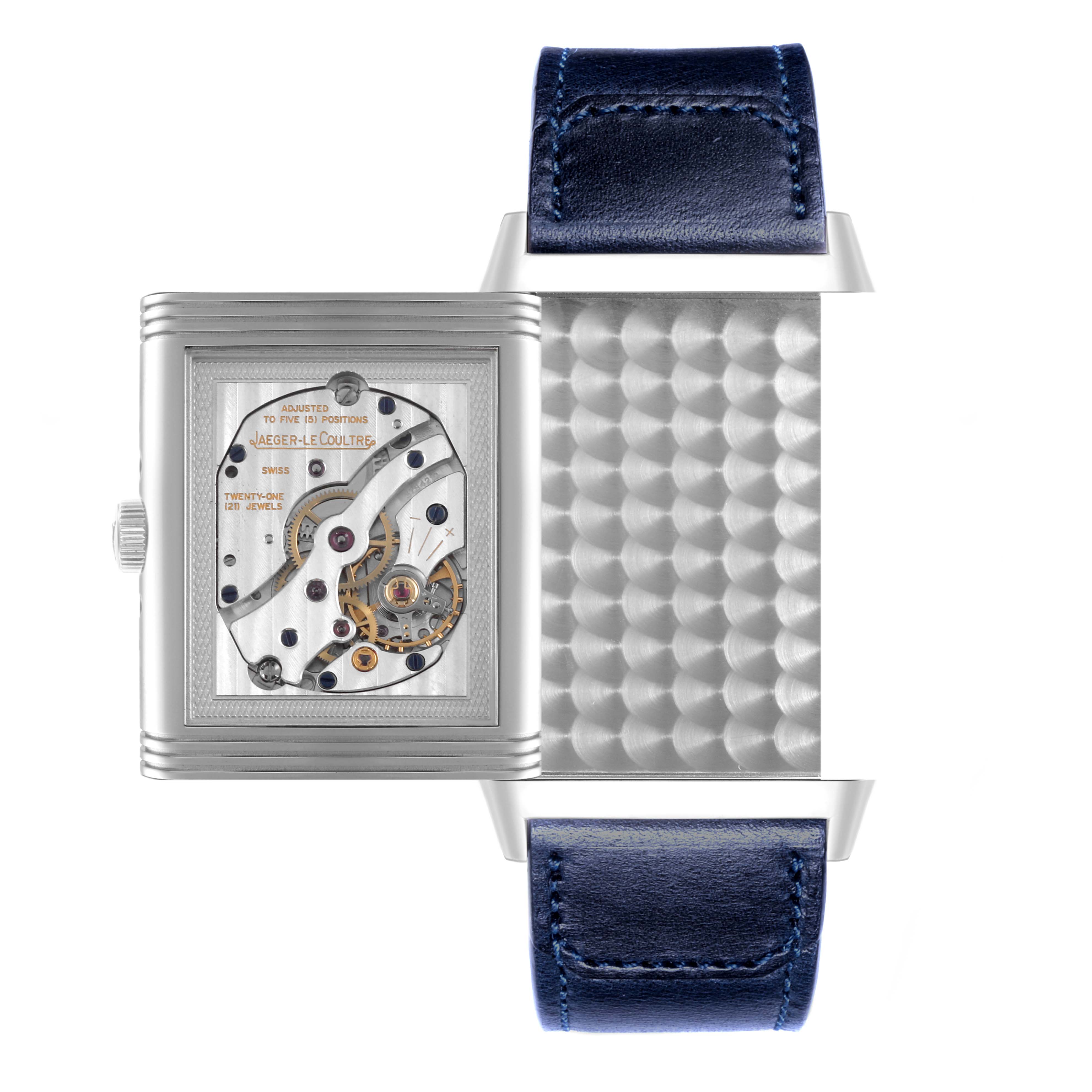 The image shows a Jaeger-LeCoultre Reverso watch from a top angle, highlighting the watch's mechanical movement and a blue leather strap.