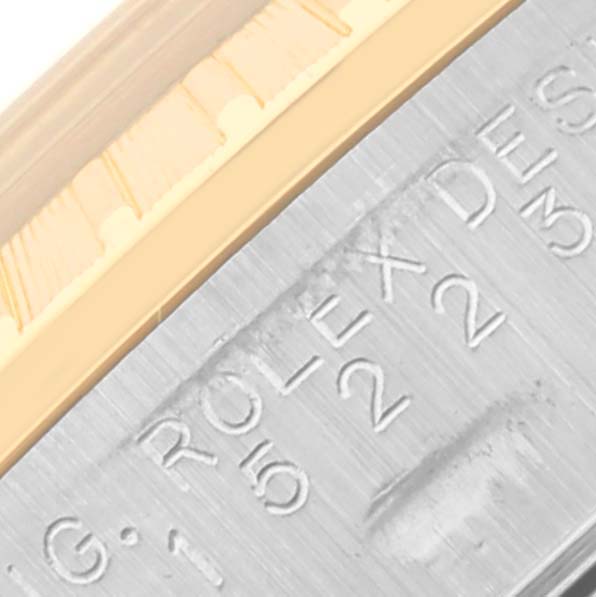 The image shows a close-up of the Rolex Date 15223 Men
s Steel and Gold (two tone) Blue Dial 15223 Men
s Steel and Gold (two tone) Blue Dial model, focusing on the engraved part of the case and the bezel
s edge.