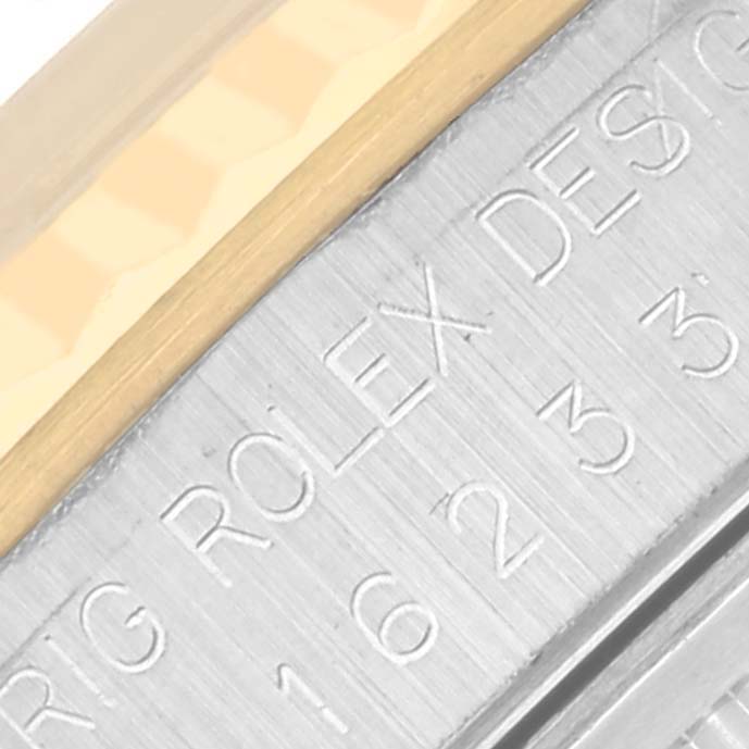 The image shows a close-up of the side of a Rolex Datejust 16233 Men's Steel and Gold (two tone) Grey Dial 16233 Men's Steel and Gold (two tone) Grey Dial case with engraved text.