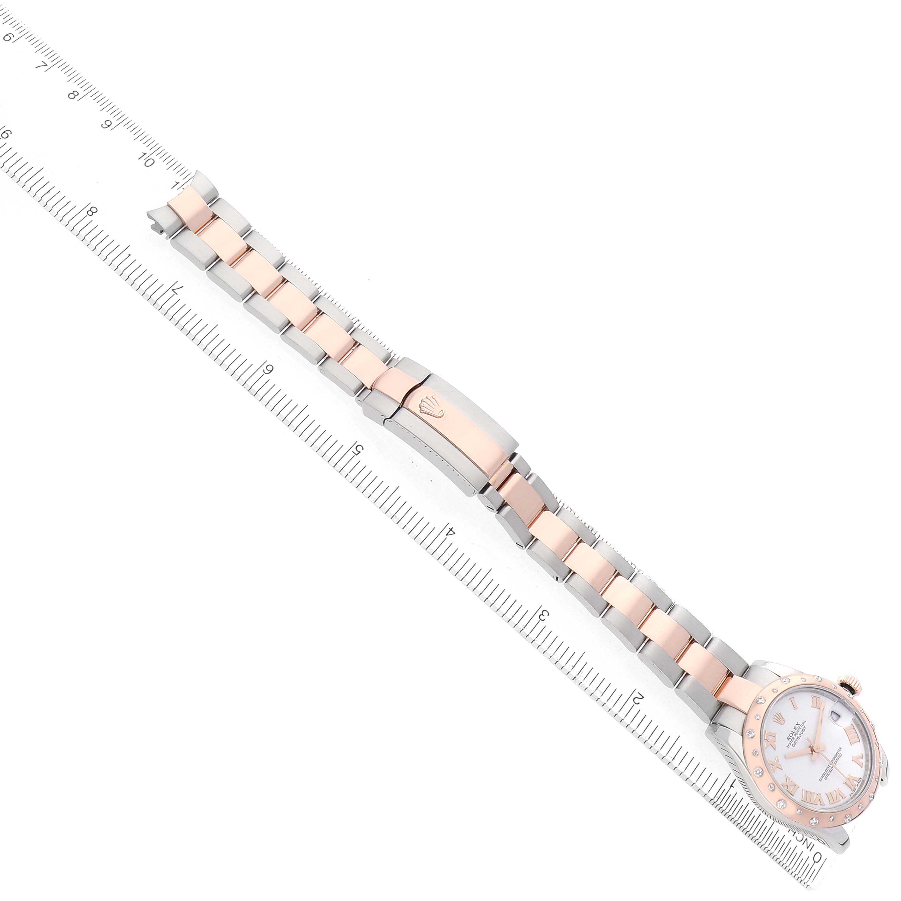 The Rolex Mid-Size 178341 Women's Steel and Gold (two tone) White Dial watch is shown from an overhead angle, featuring the band, clasp, and face alongside a ruler for scale.