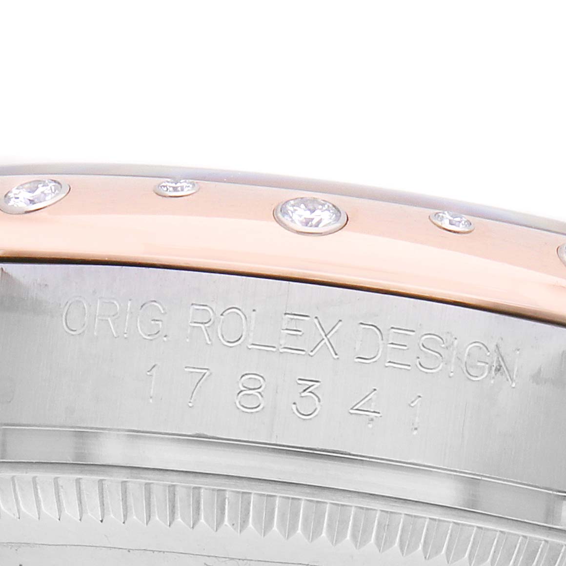 The image shows a side view focusing on the bezel with diamonds and engraved details of the Rolex Mid-Size 178341 Women's Steel and Gold (two tone) White Dial model.
