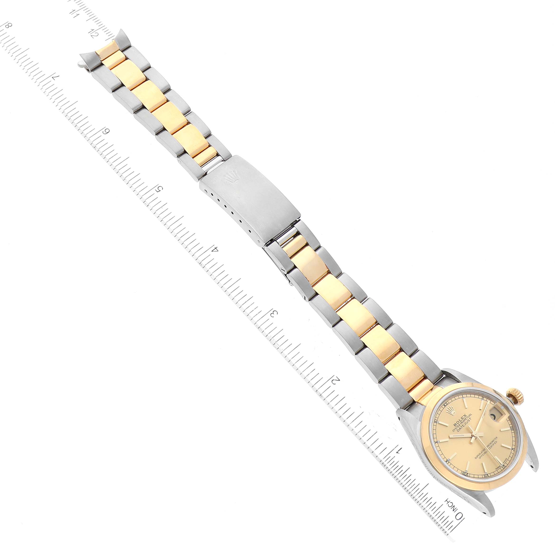 The image shows a top view of a Rolex Mid-Size 68243 Women
s Steel and Gold (two tone) Champagne Dial 68243 Women
s Steel and Gold (two tone) Champagne Dial watch, featuring the dial, case, two-tone bracelet, and clasp, positioned next to a ruler.