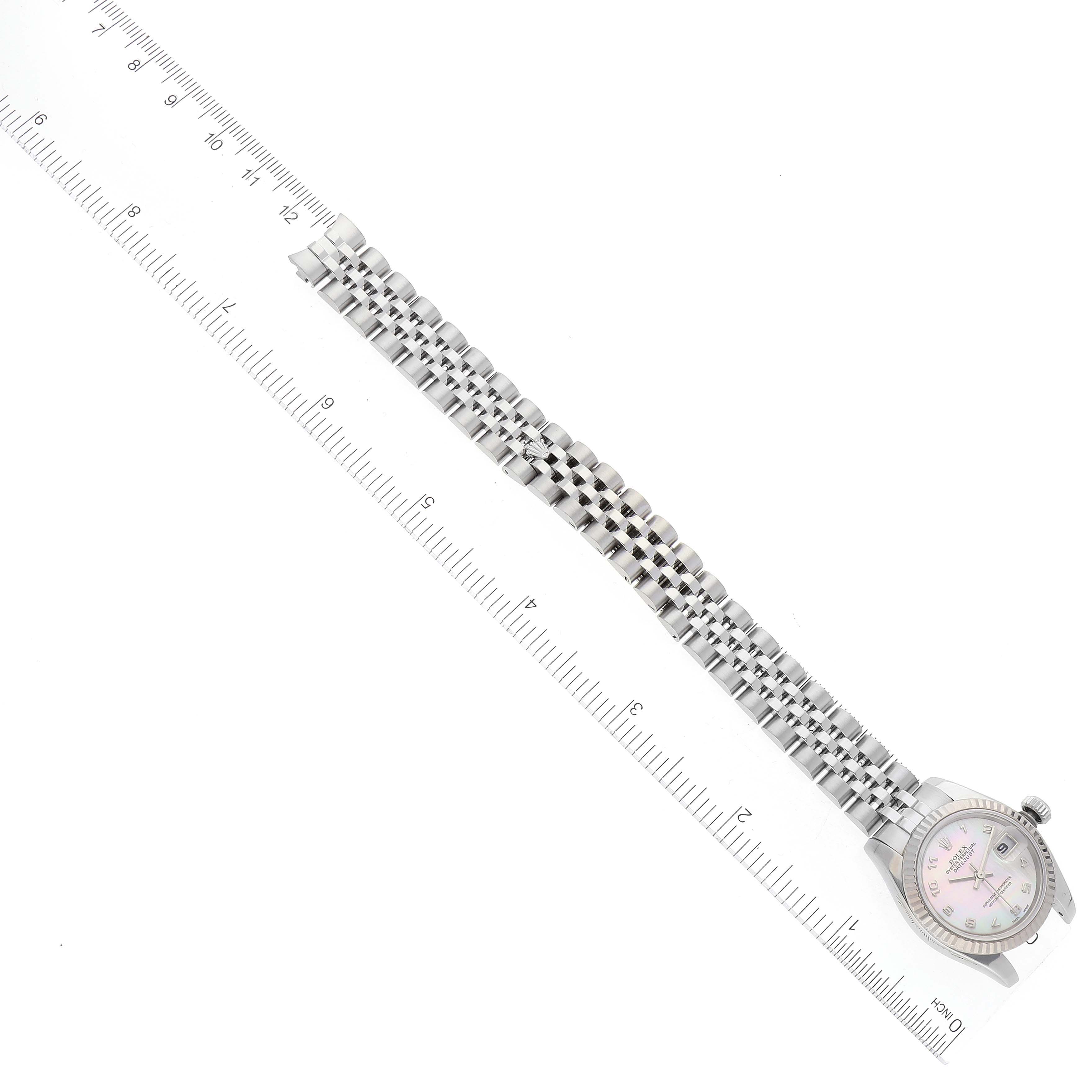 The image shows a top-down view of a Rolex Datejust 179174 Women's Stainless Steel Mother of Pearl Dial 179174 Women's Stainless Steel Mother of Pearl Dial watch, featuring the face, bezel, and bracelet next to a ruler for scale.